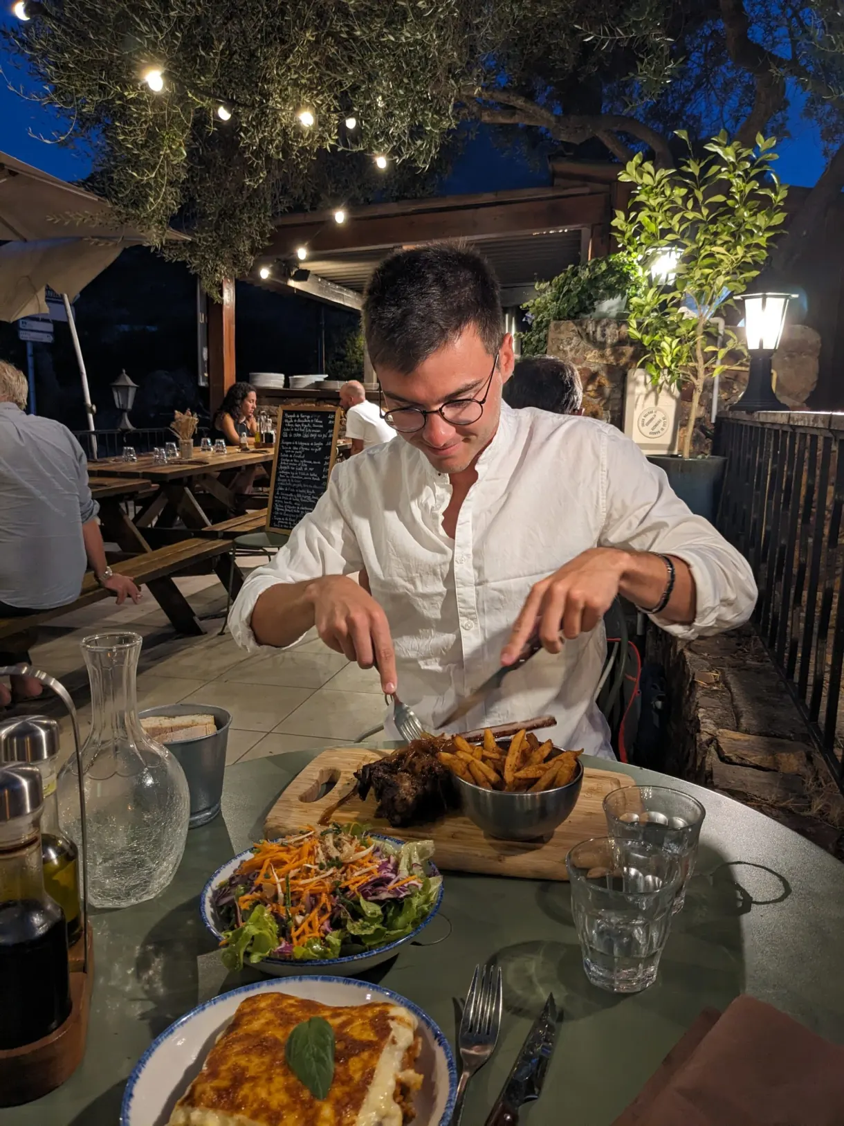 Convive découpant son plat sous les guirlandes du restaurant