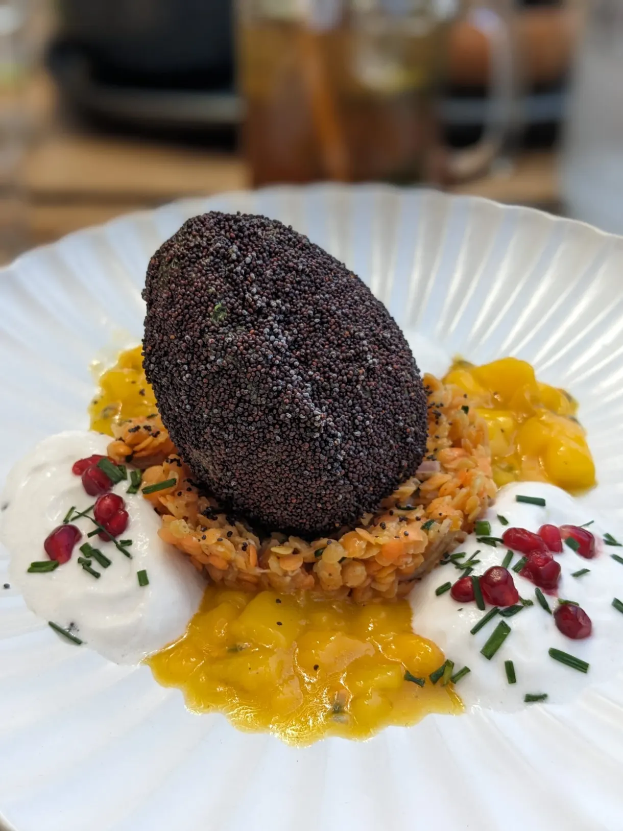 Assiette gastronomique sombre posée sur un coulis safrané