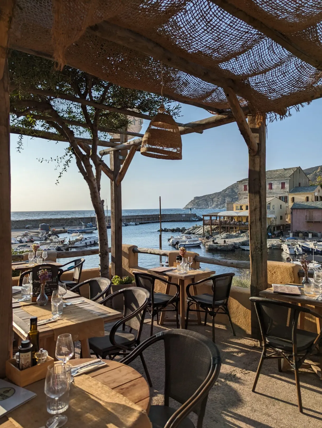 Terrasse sous pergola donnant sur un petit port de pêche