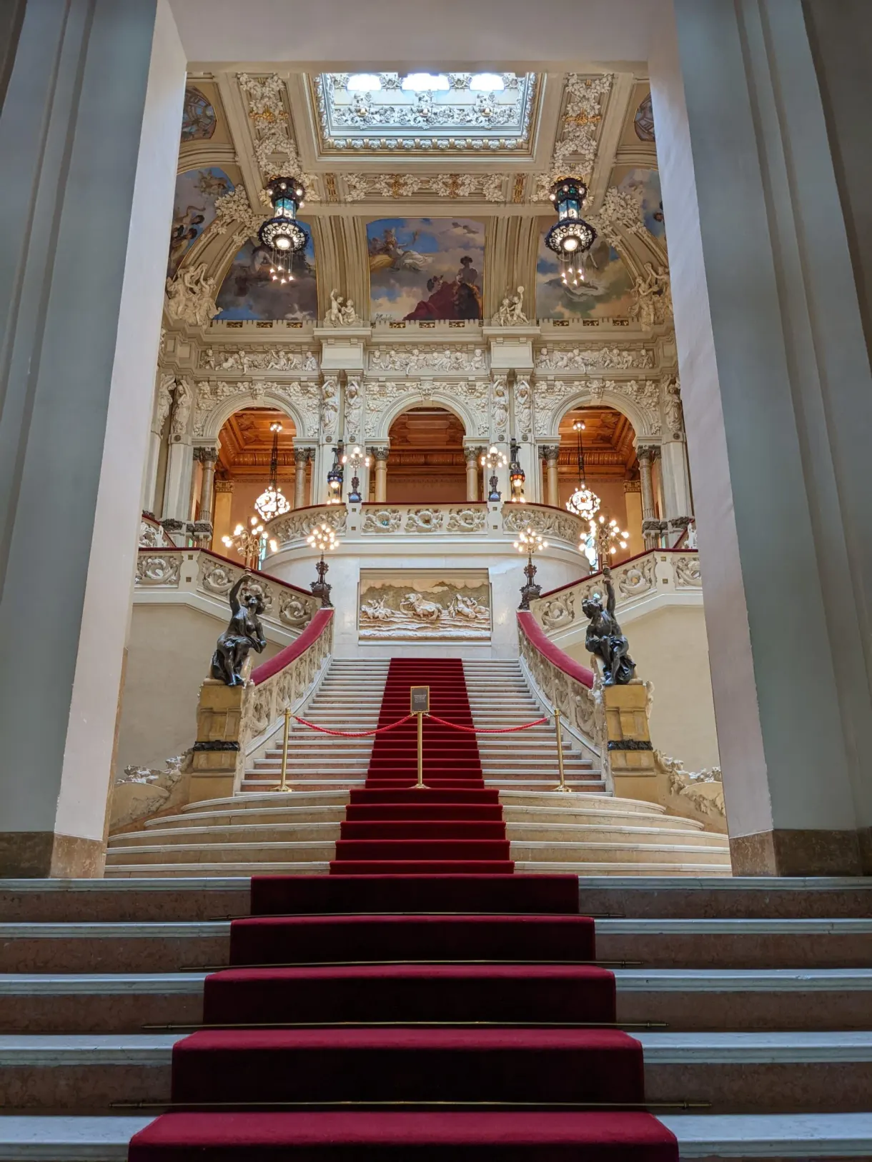 Escalier d'honneur et son tapis rouge sous les fresques