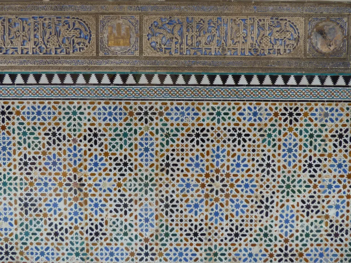 Mur de zelliges bleus et ocres sous une frise sculptée