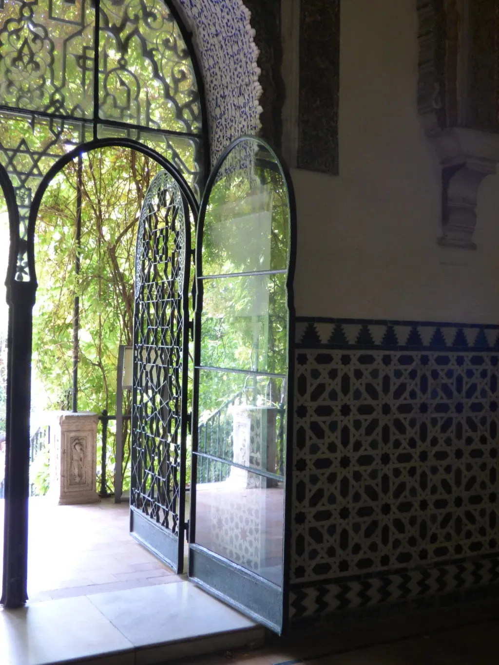 Porte en fer forgé ouverte sur la verdure du jardin