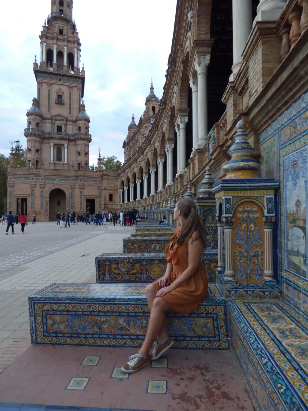 Femme en robe ocre assise sur un banc d'azulejos
