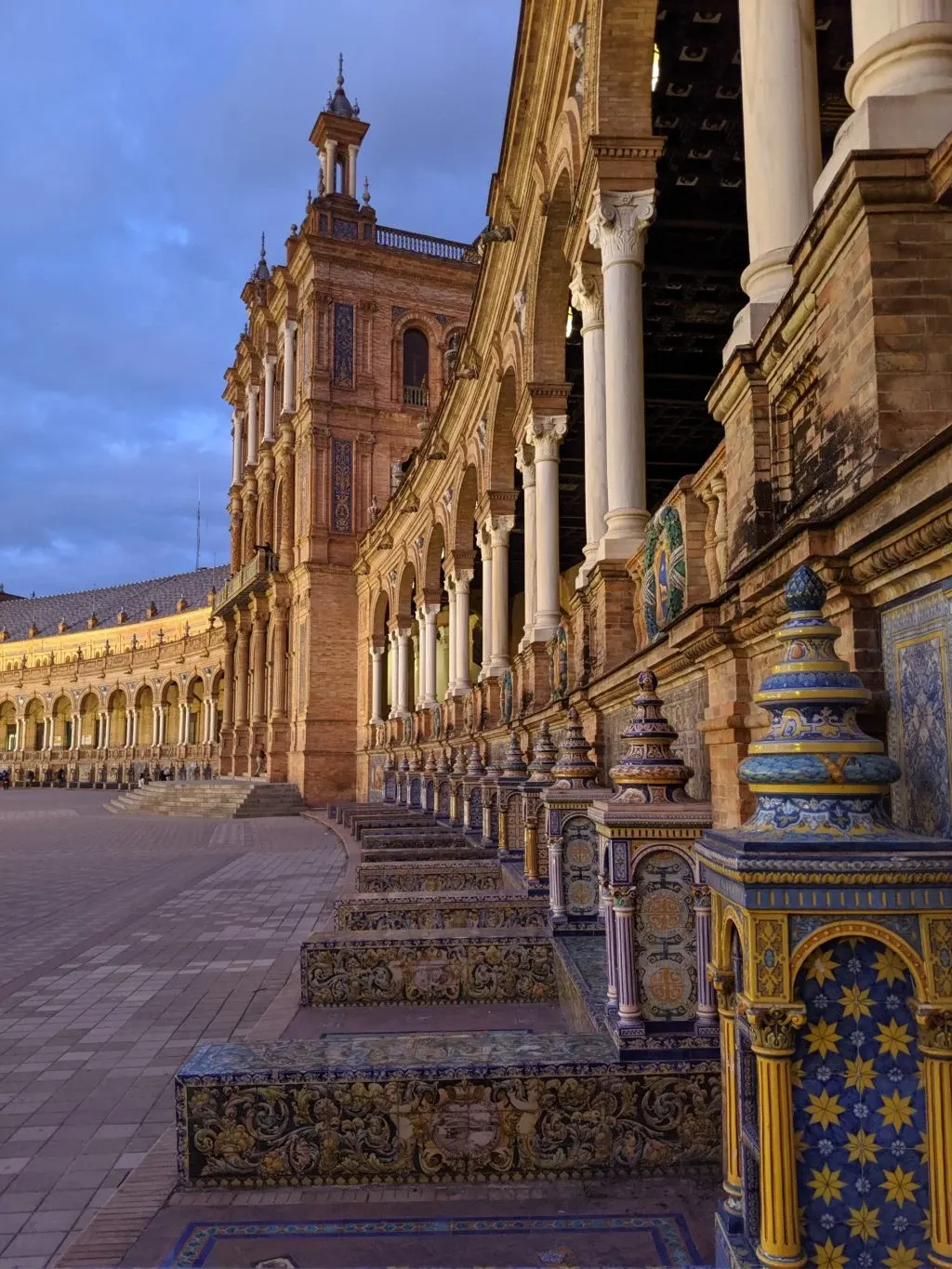 Galerie à colonnes et bancs de faïence au soleil couchant