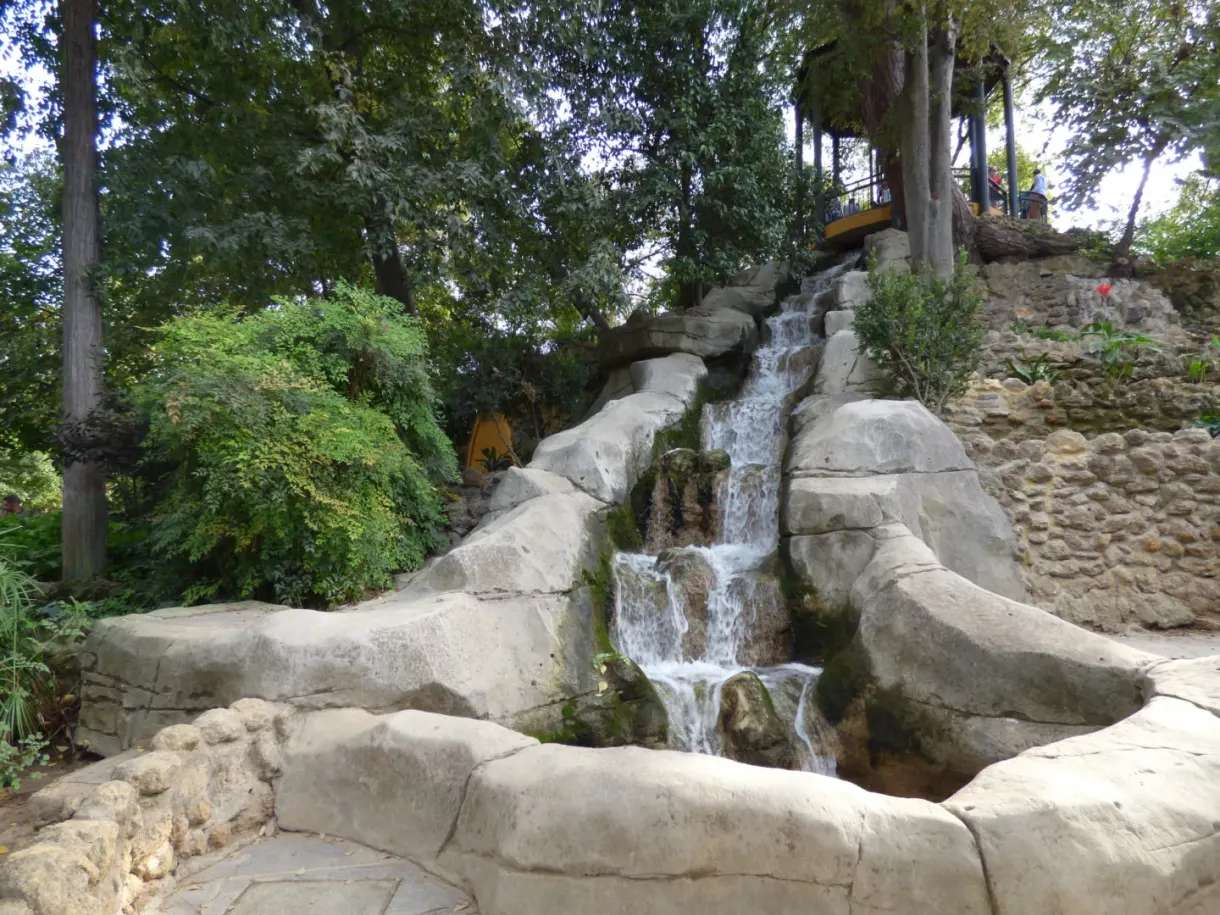 Cascade artificielle dévalant un rocher au milieu de la végétation