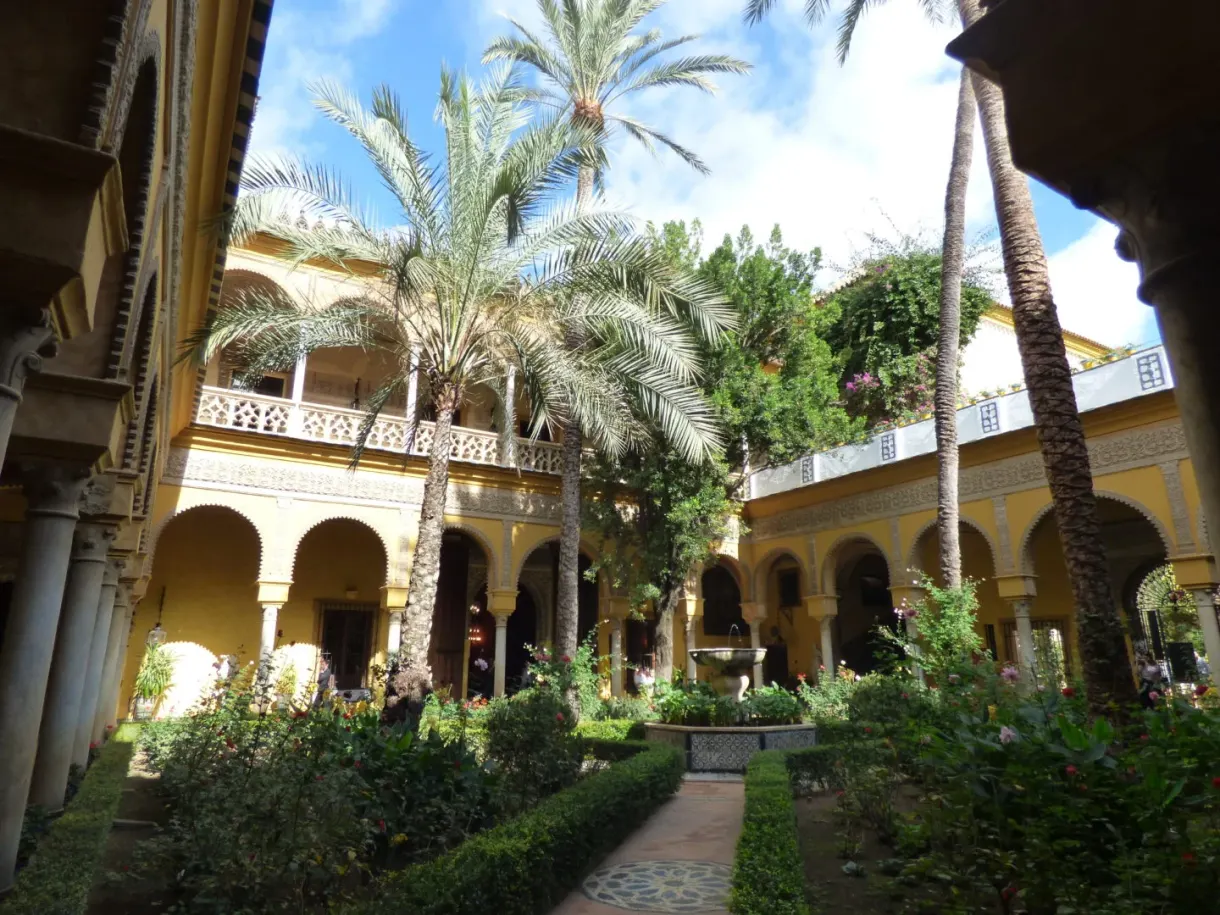 Patio à arcades blanches, palmiers et parterres fleuris
