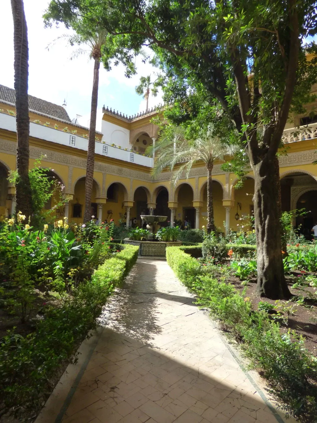 Allée pavée bordée de buis, fontaine au fond du patio