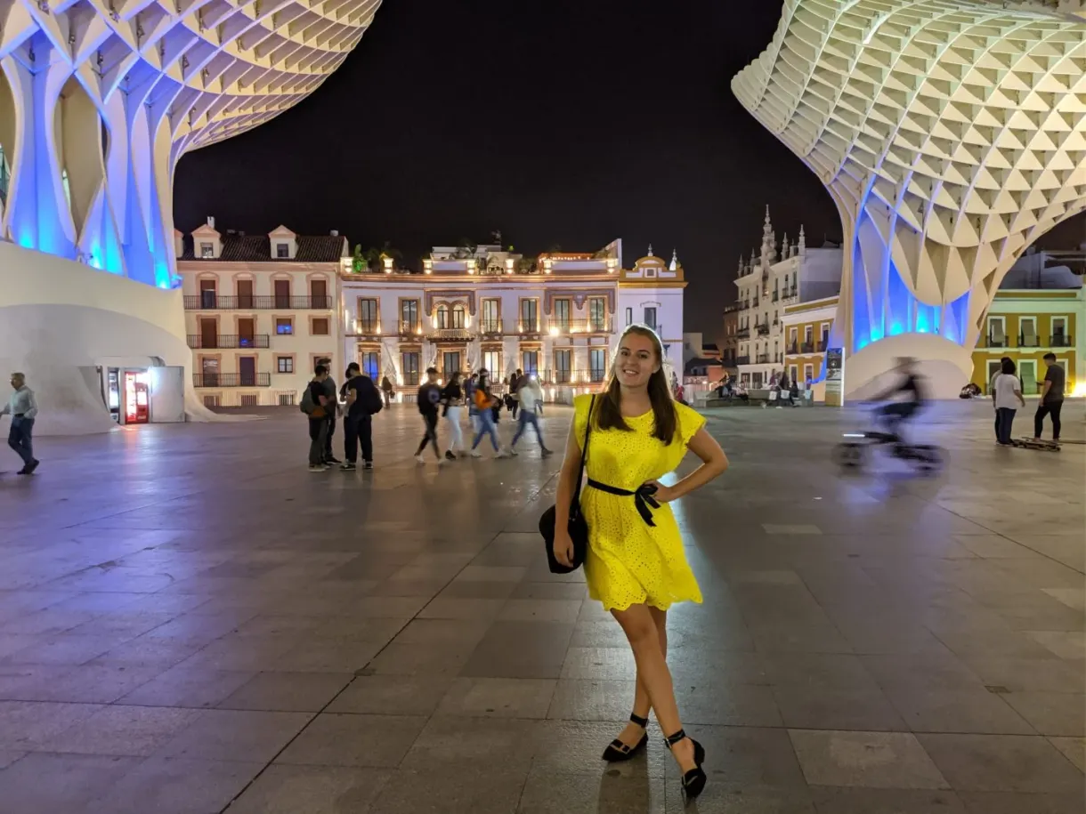 Femme en robe jaune sur la place éclairée de nuit
