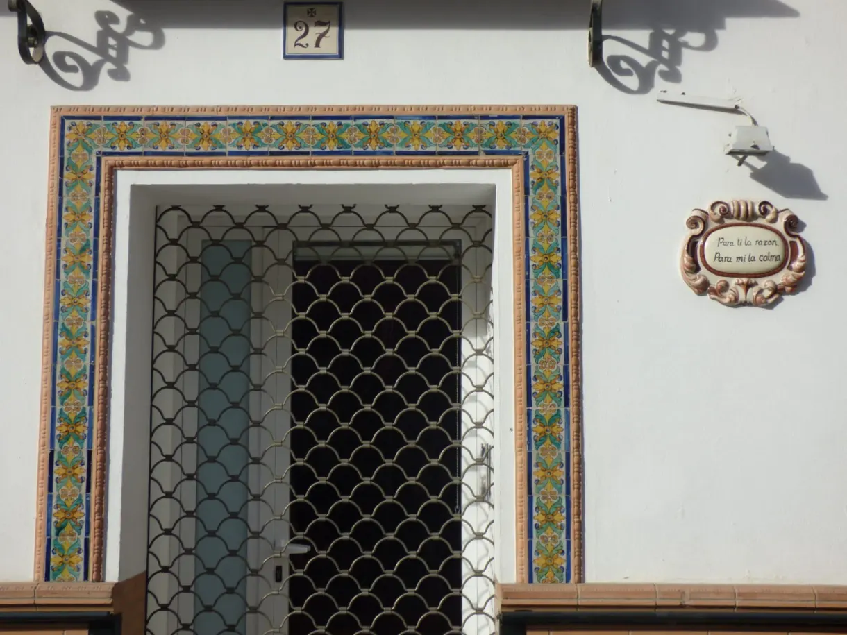 Porte encadrée d'azulejos fleuris sur une façade blanche