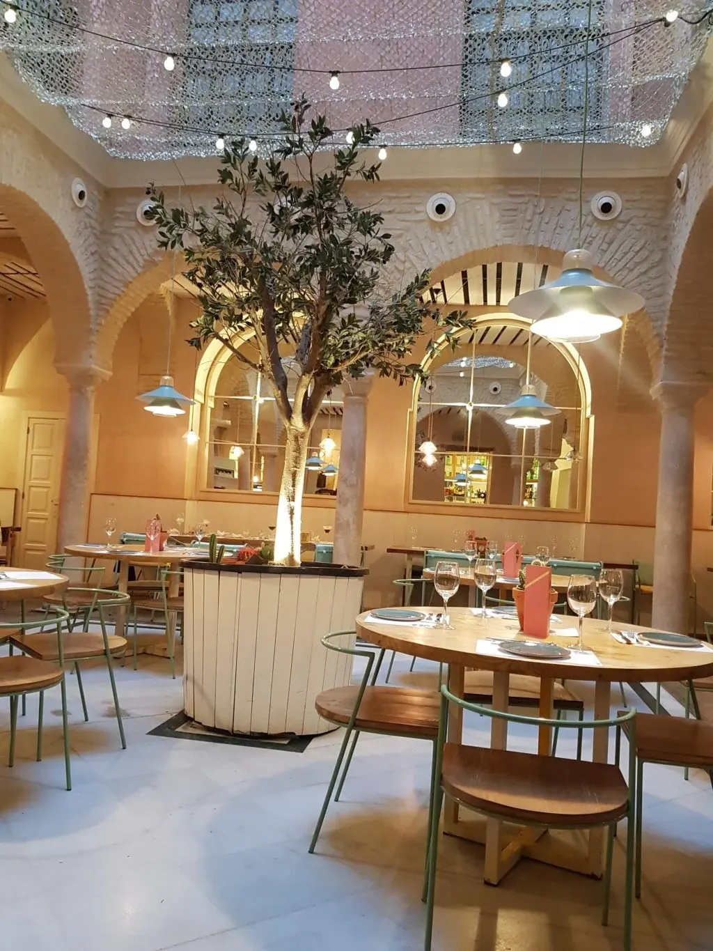 Tables rondes sous les arcades et olivier en pot