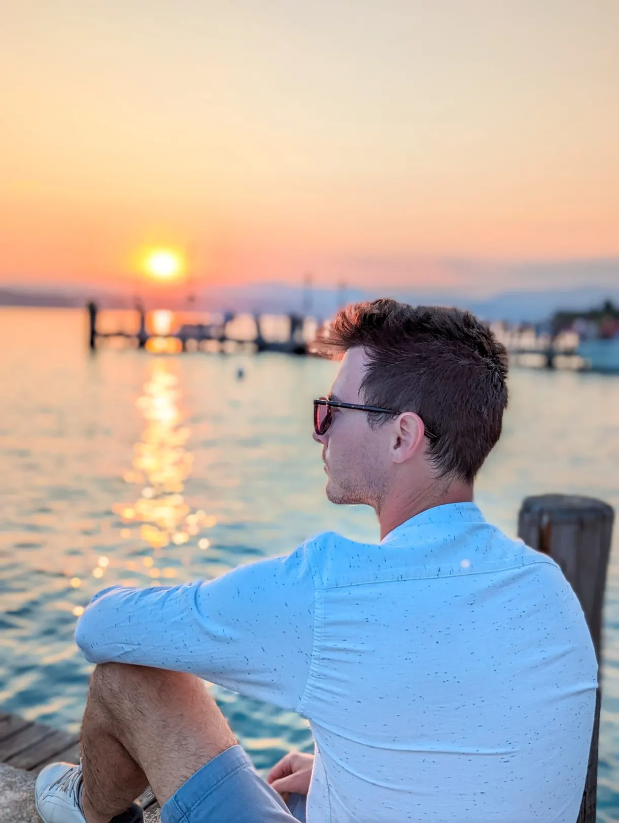 Homme contemplant le coucher de soleil au bord du lac