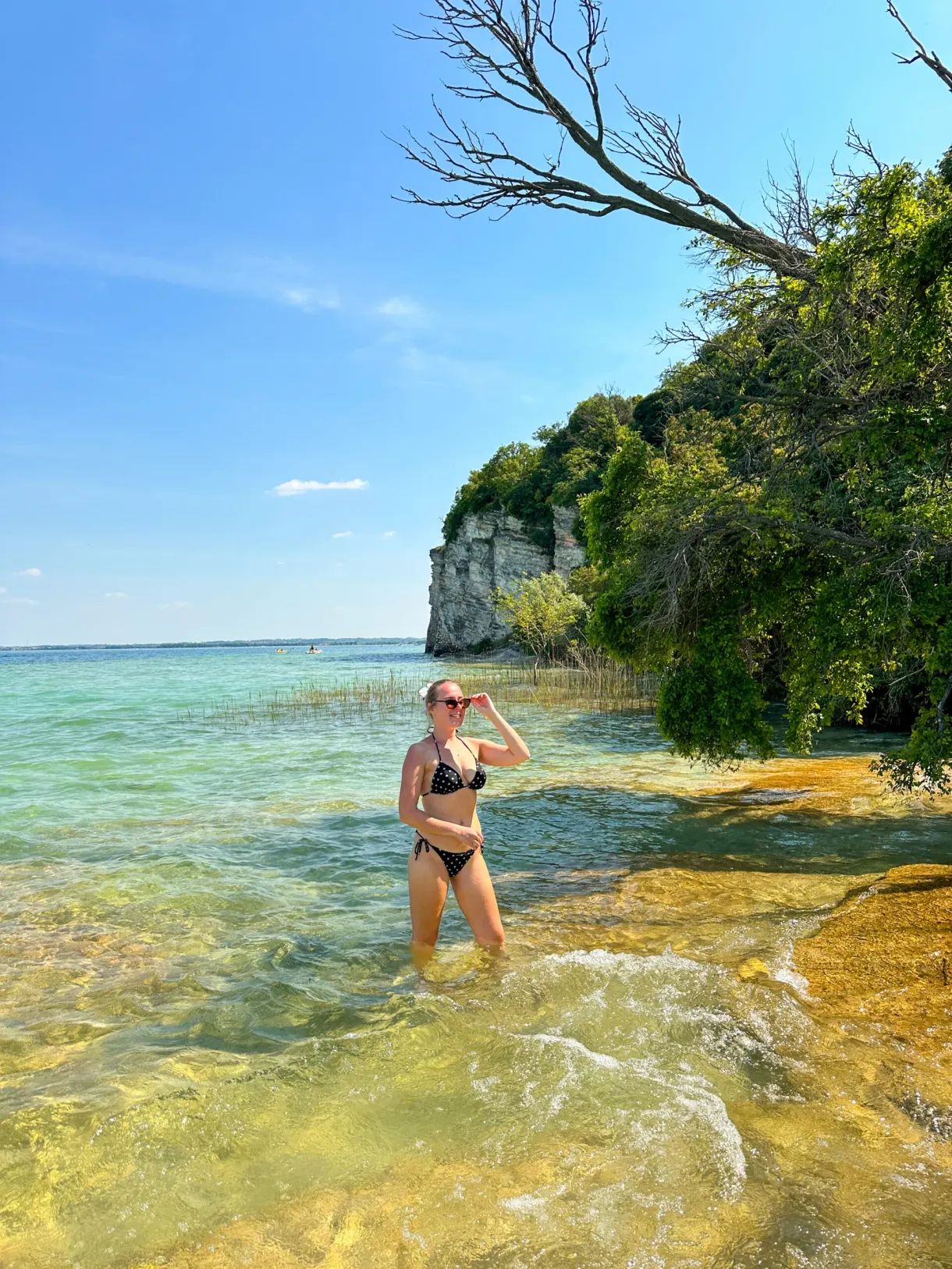 Baigneuse dans l'eau translucide près d'une pointe boisée