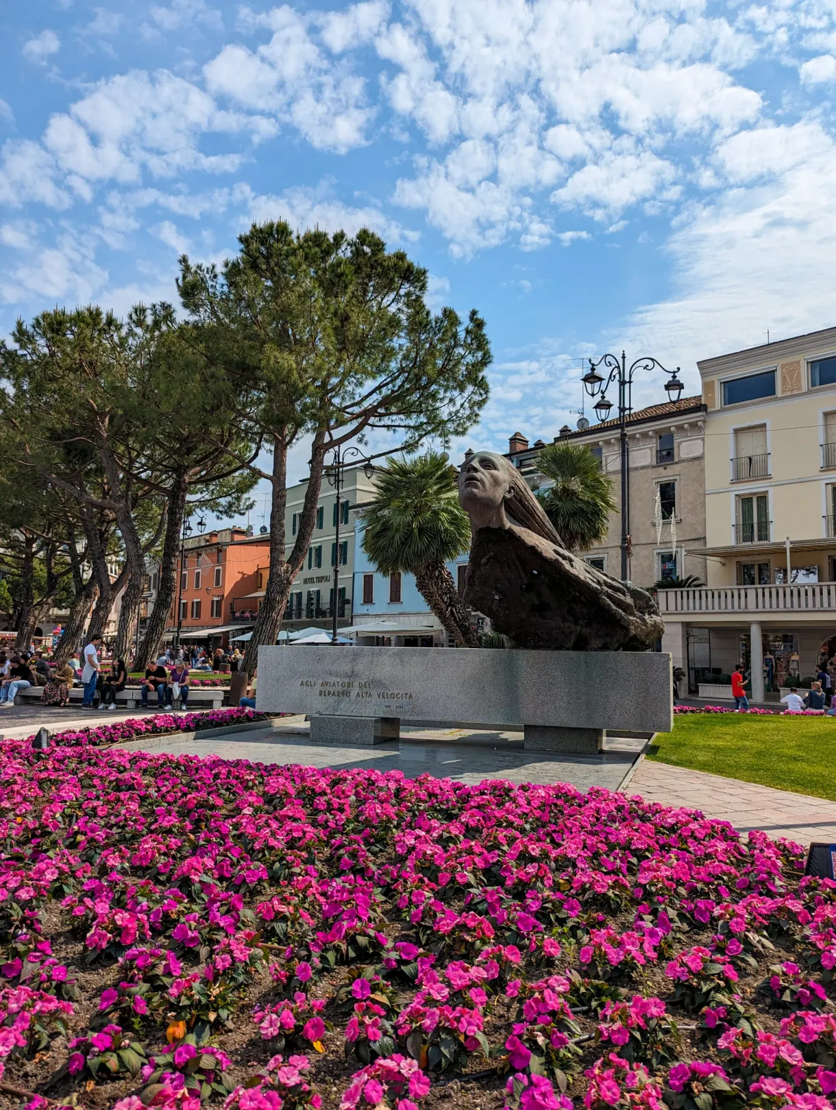 Massif de fleurs roses devant une statue de bronze