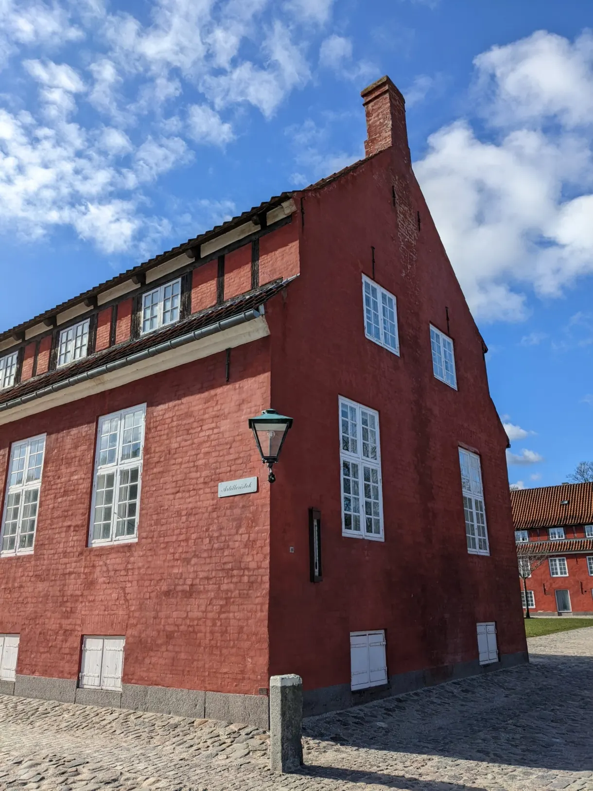 Pignon d'un grand entrepôt rouge à fenêtres blanches, ciel dégagé
