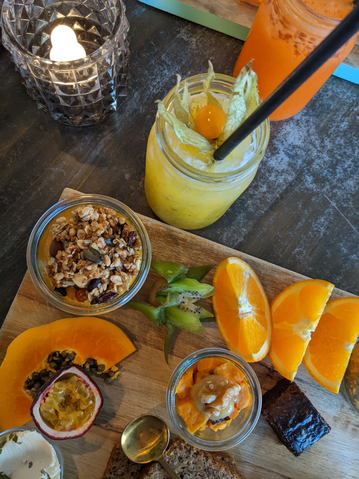 Jus d'orange, granola et fruits frais servis sur une planche de bois