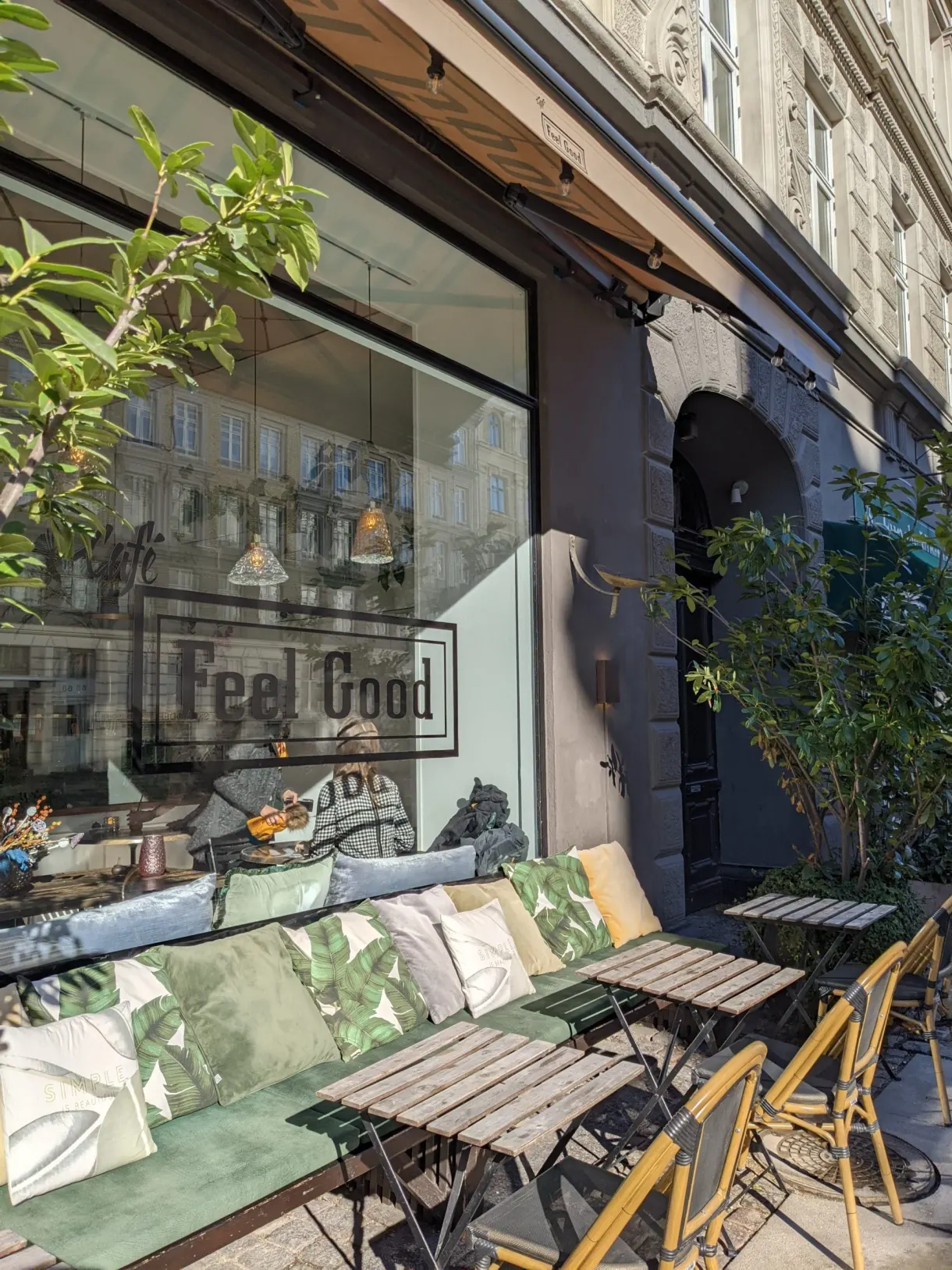 Devanture de café avec banquette fleurie et tables en terrasse