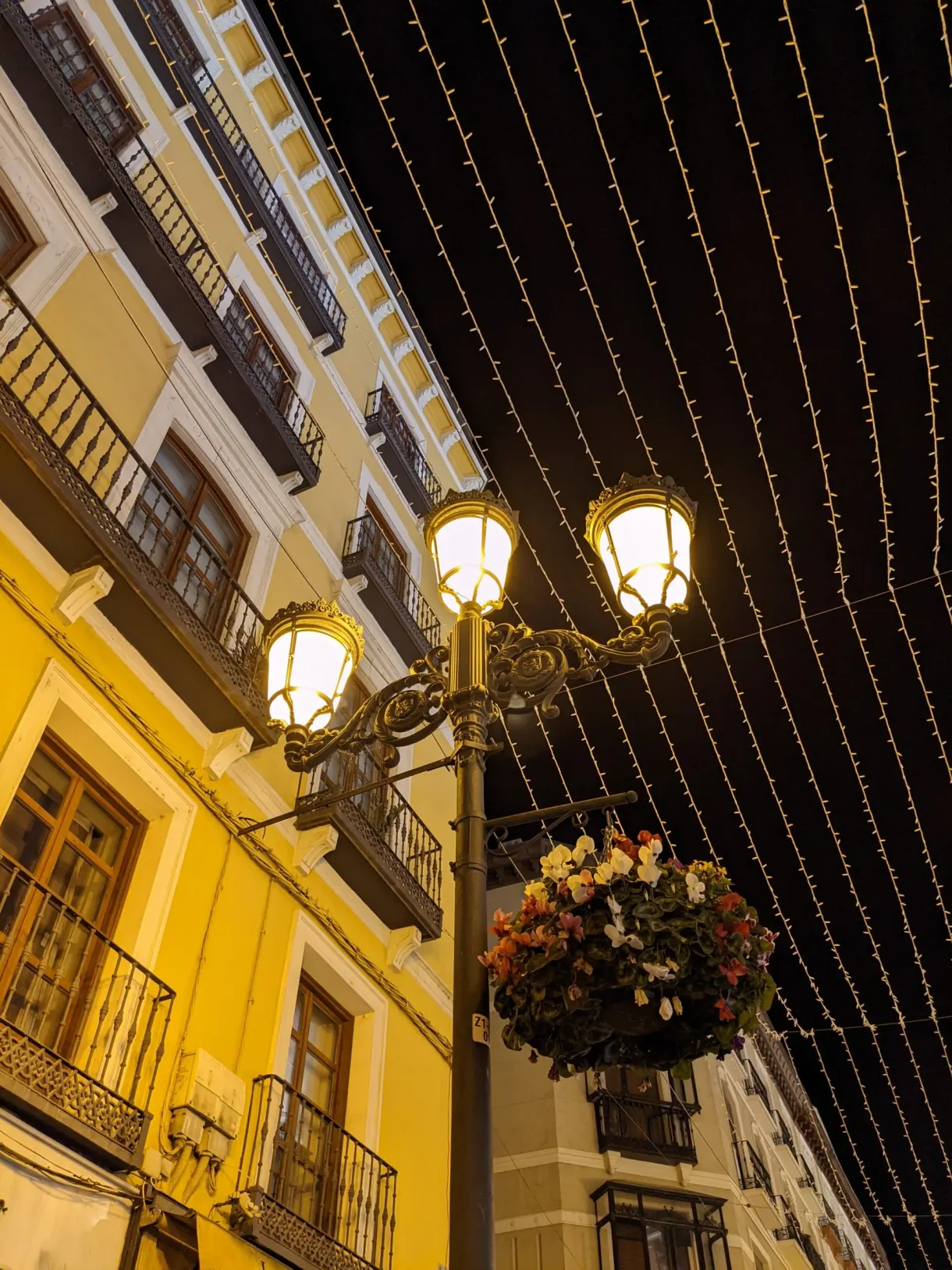 Lampadaires et guirlandes au-dessus d'une façade jaune