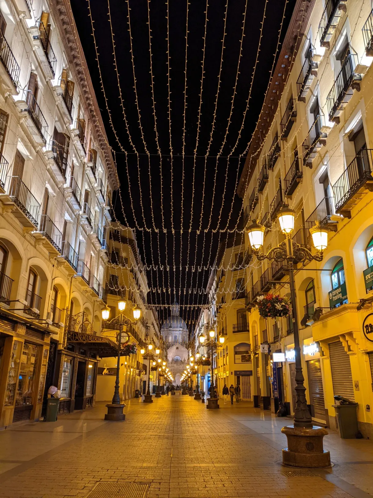 Rue commerçante illuminée par un ciel de guirlandes