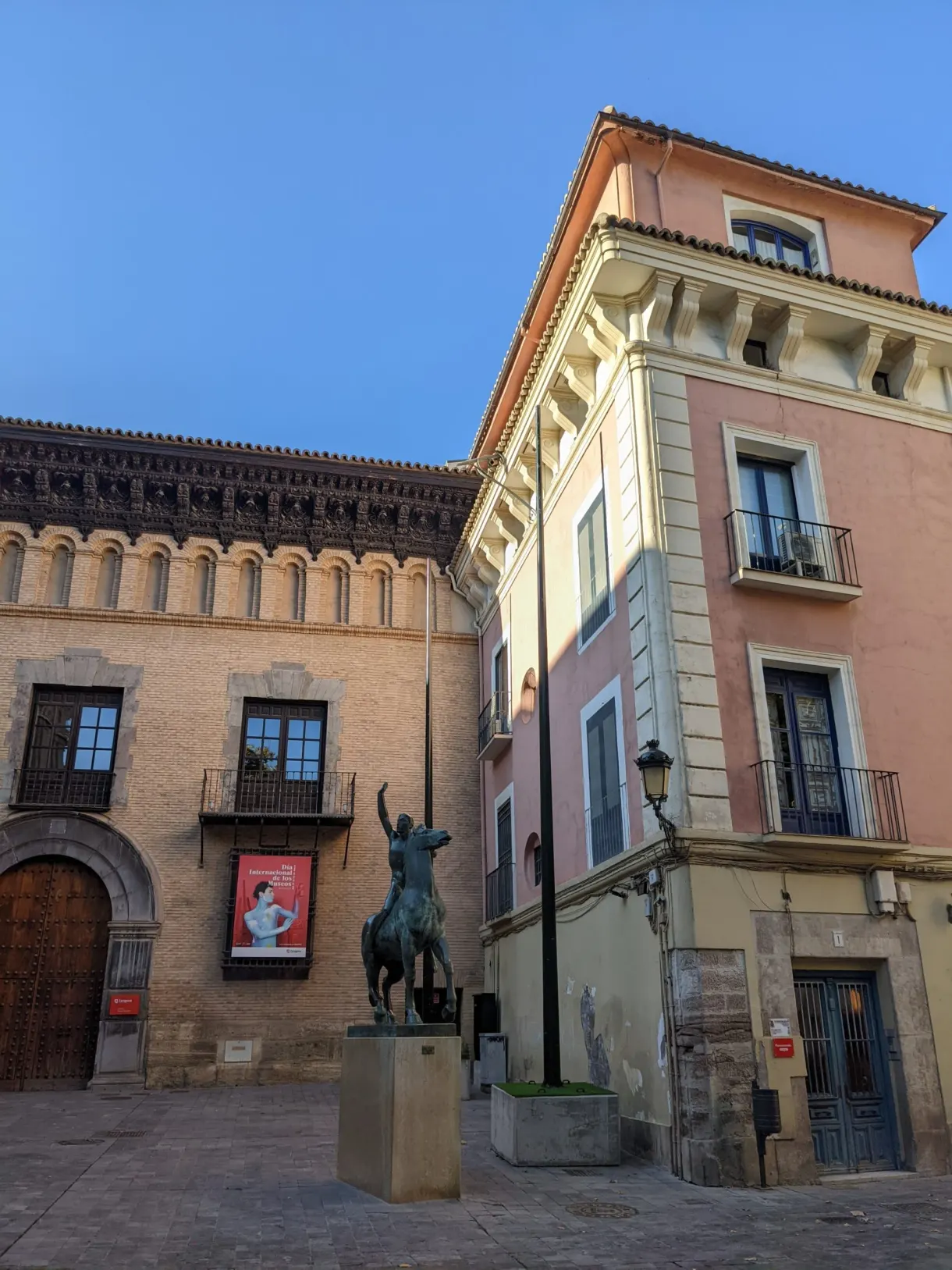 Statue équestre devant des façades roses et ocres