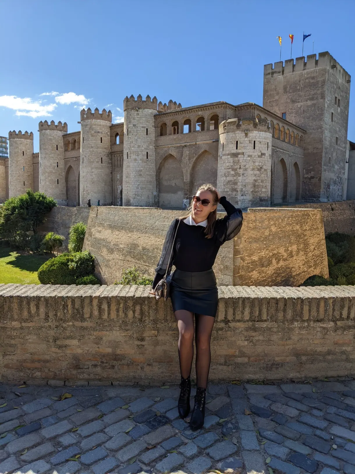 Femme accoudée à un muret face au palais fortifié