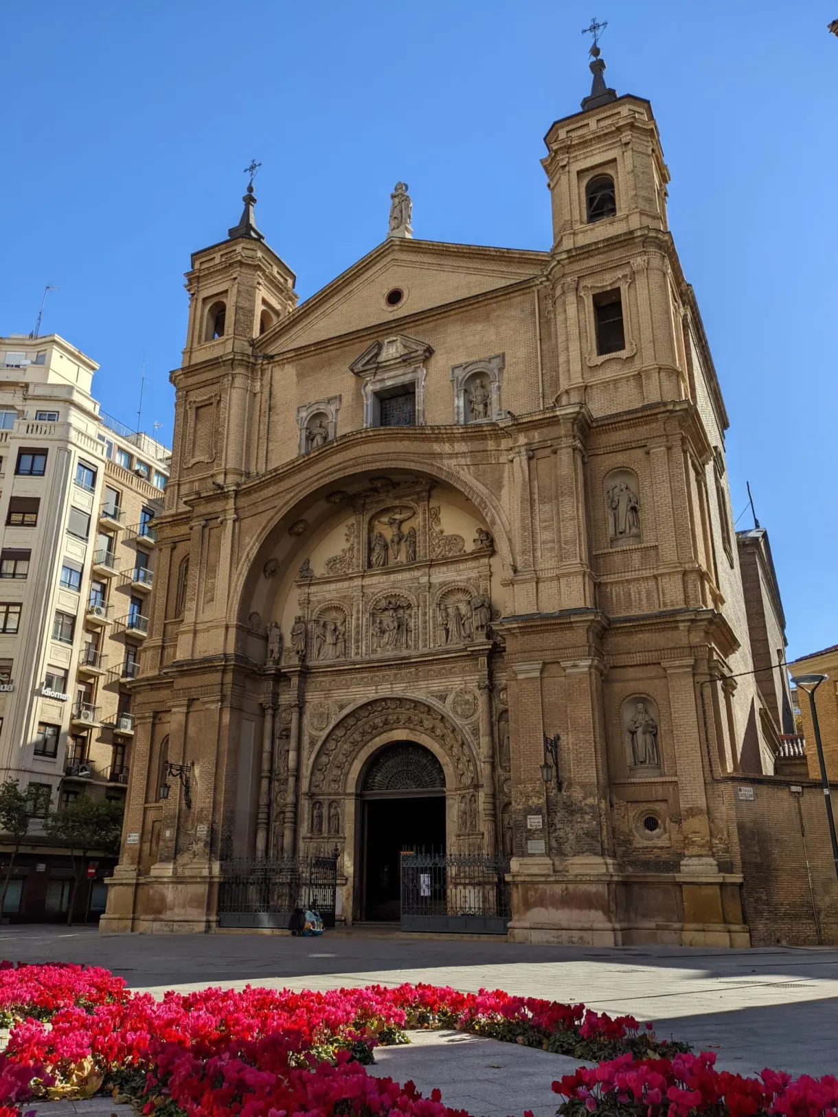 Église baroque devant un parterre de fleurs rouges