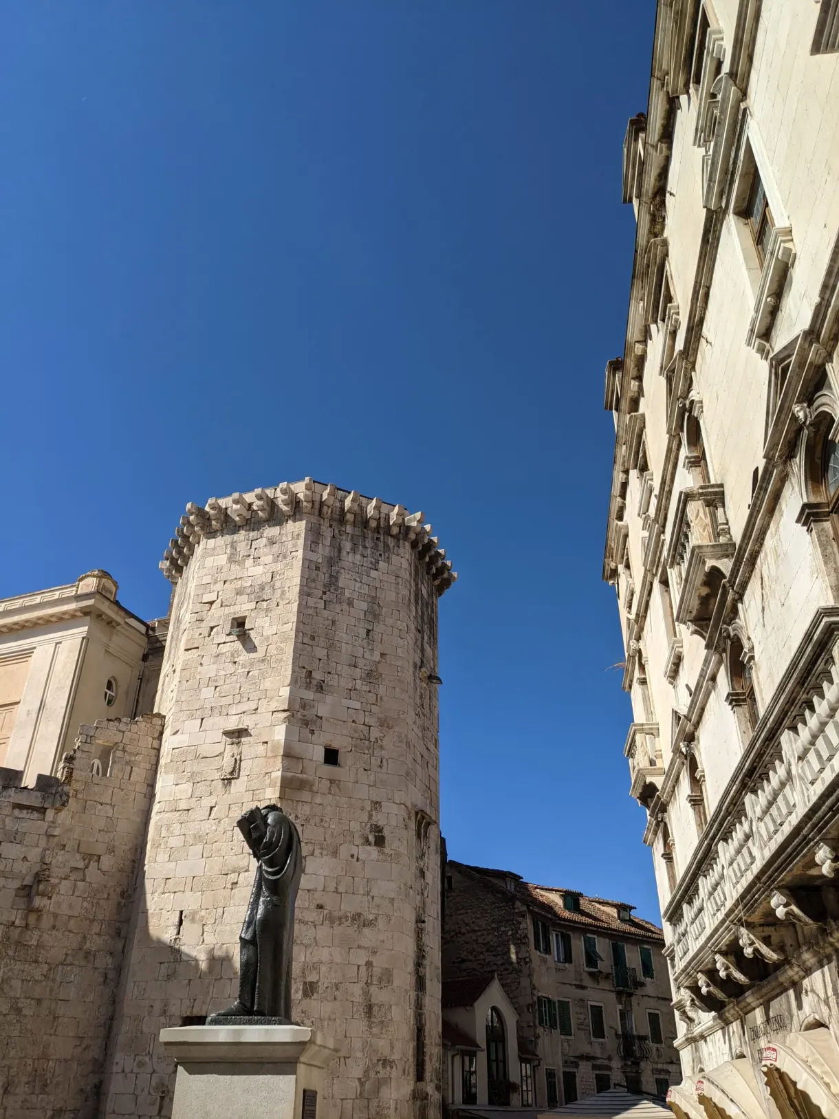 Tour carrée en pierre en contre-plongée entre deux façades
