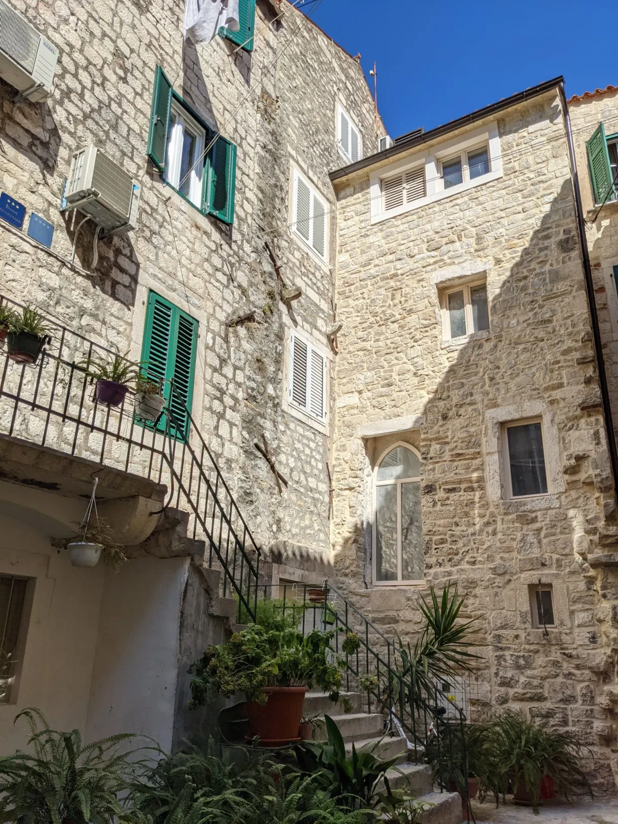 Cour intérieure en pierre avec escalier extérieur et plantes en pots