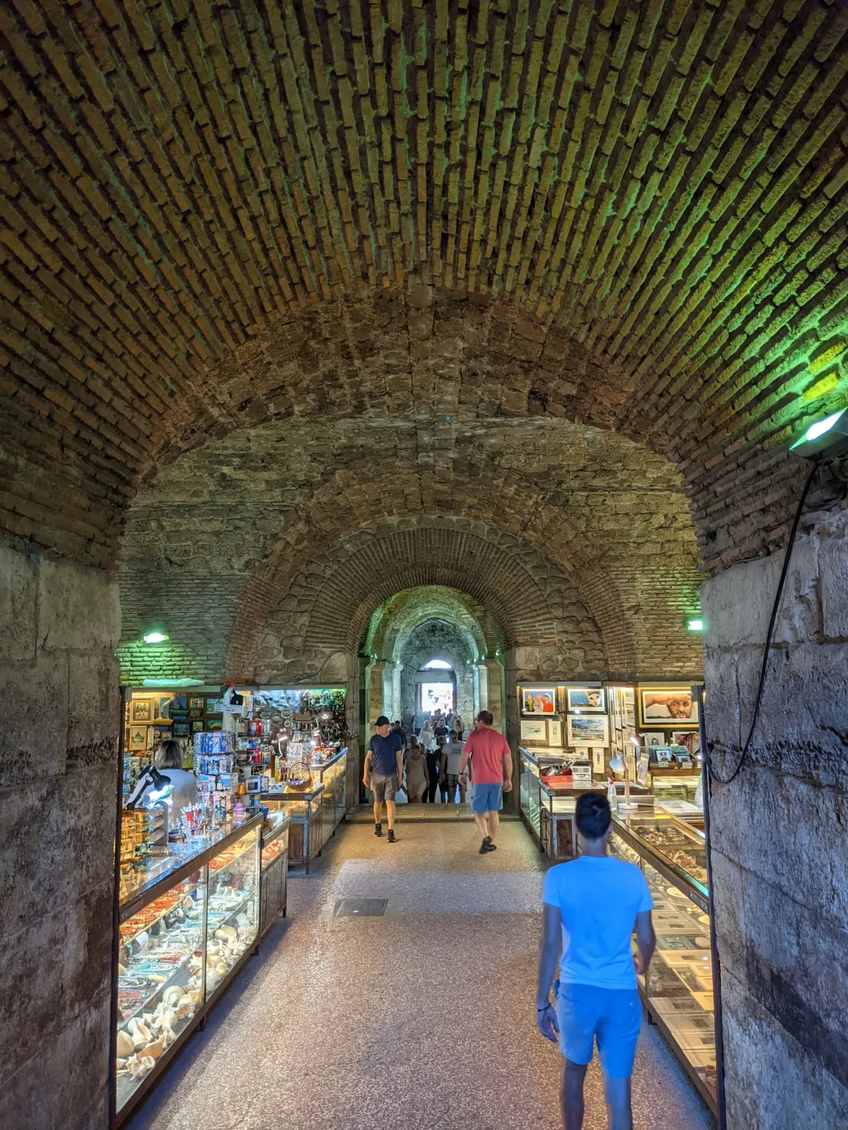 Galerie voûtée occupée par des étals de souvenirs