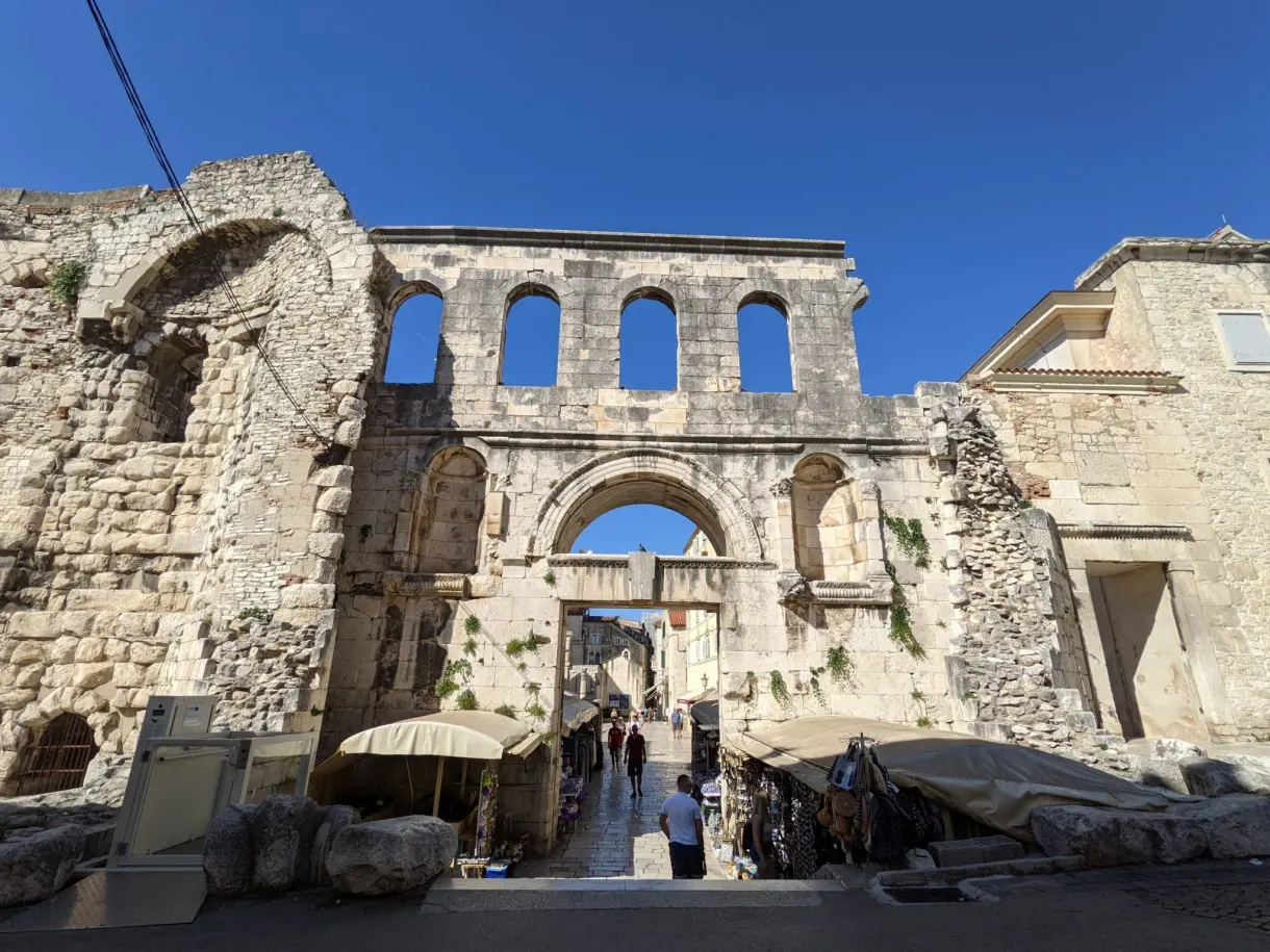 Porte romaine en ruines et étals installés au pied des arcades