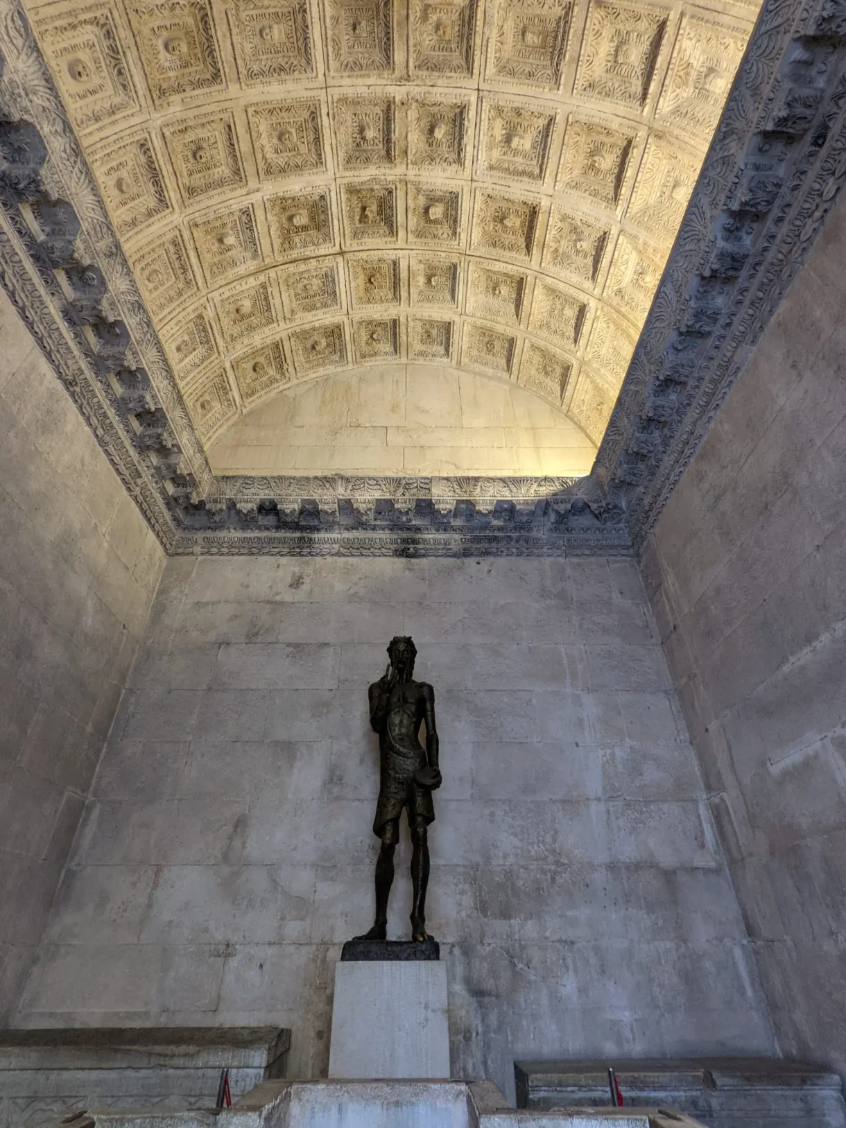 Statue de bronze sous un plafond à caissons sculptés