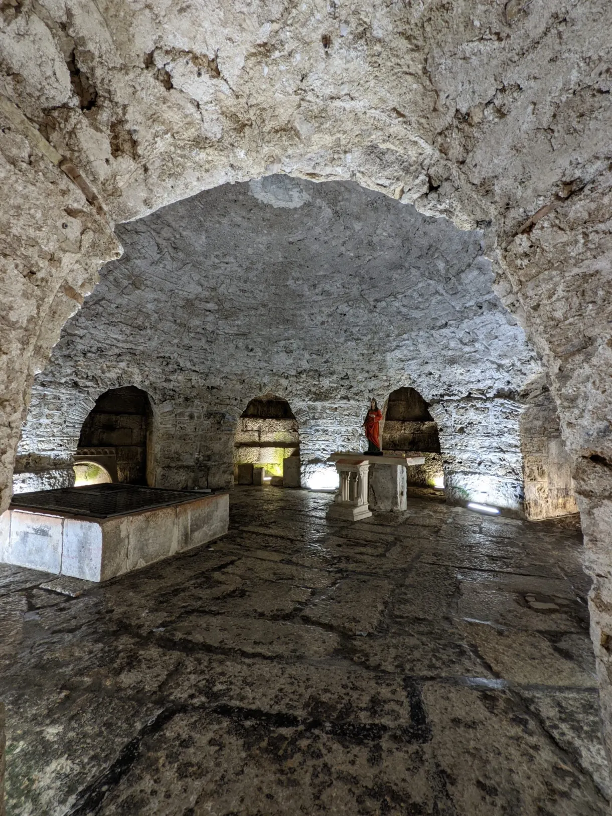 Crypte voûtée au sol dallé et aux murs de pierre brute