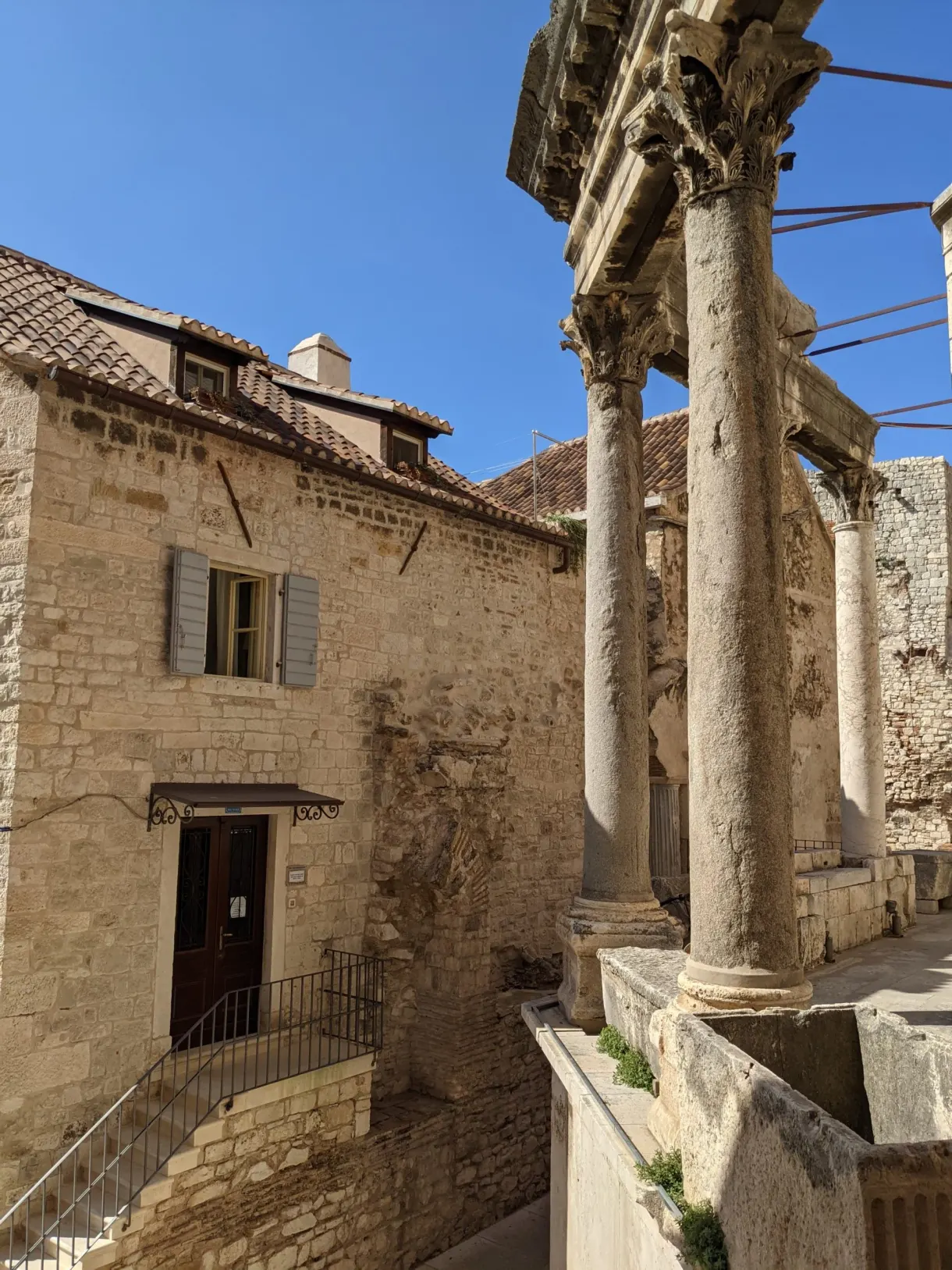 Colonnes antiques devant une maison de pierre à volets