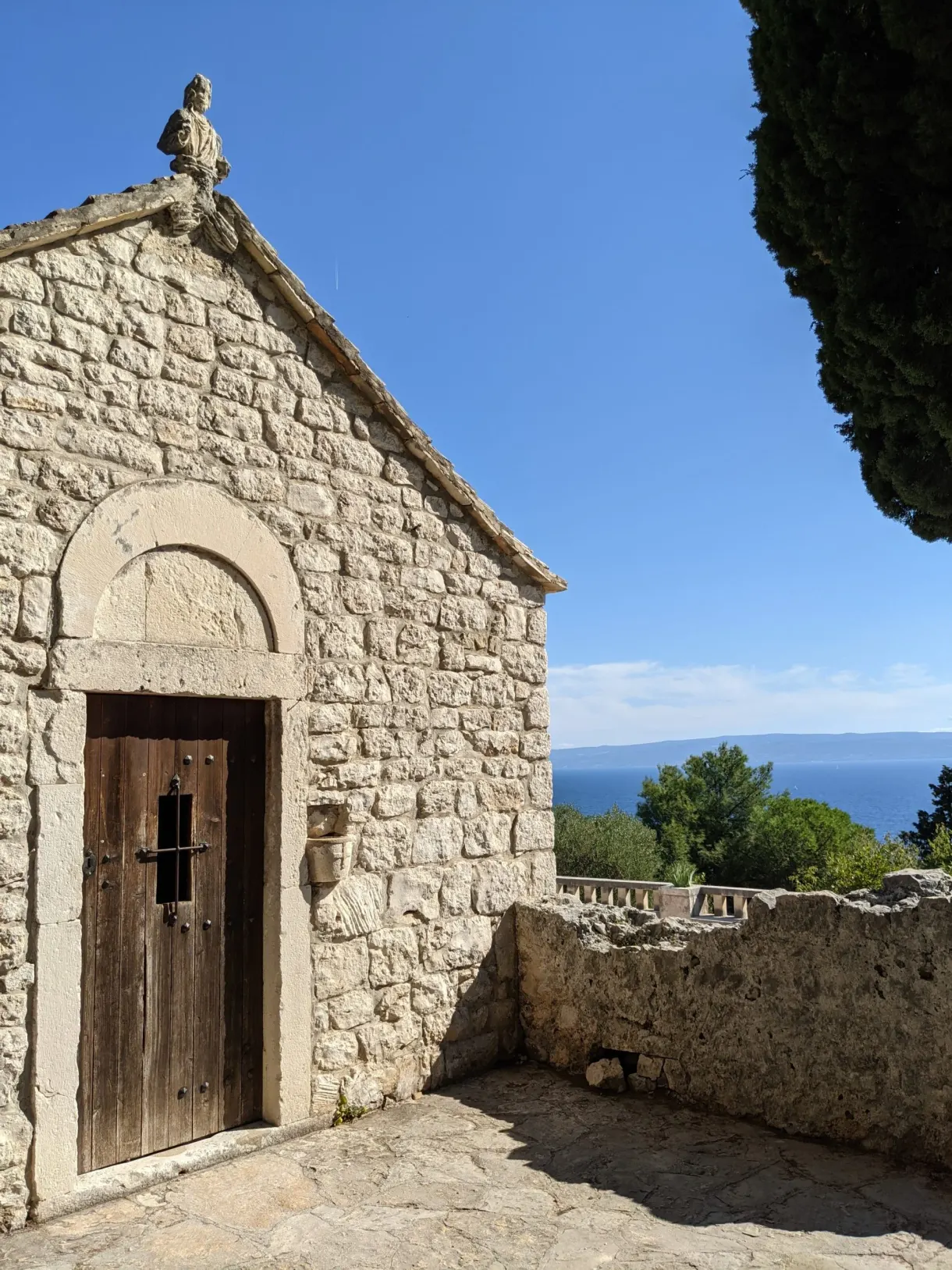 Petite chapelle en pierre à porte de bois et cyprès