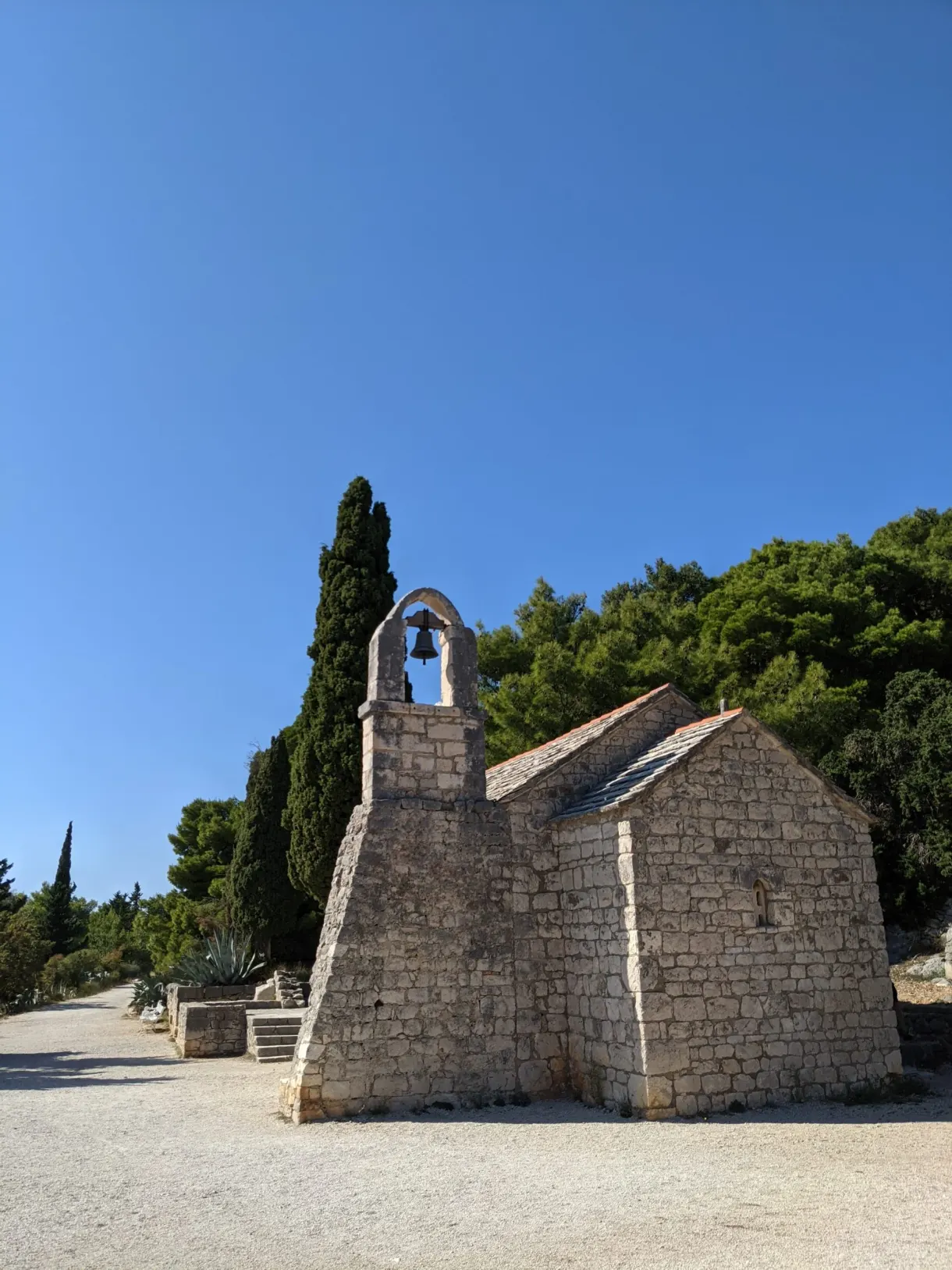 Chapelle blanche à clocheton au bout d'un chemin de gravier