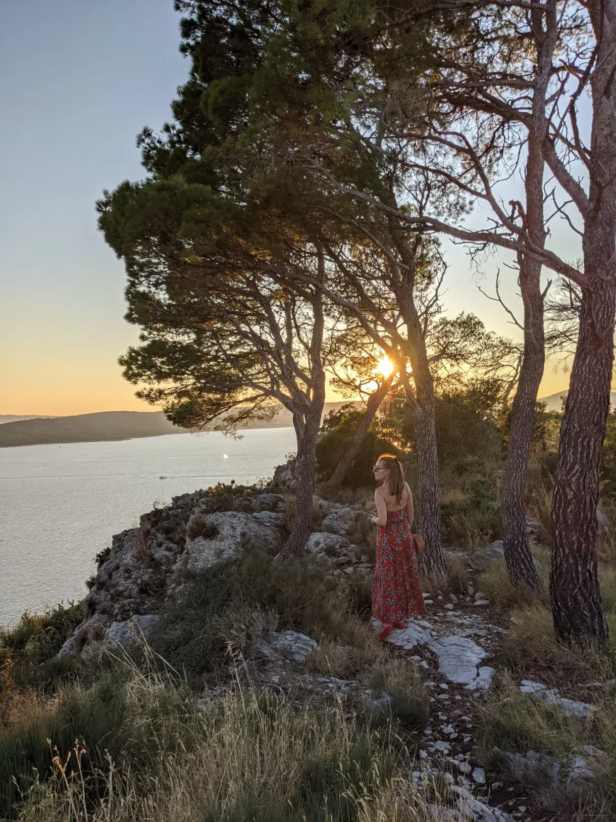 Femme en robe rouge sous les pins à contre-jour