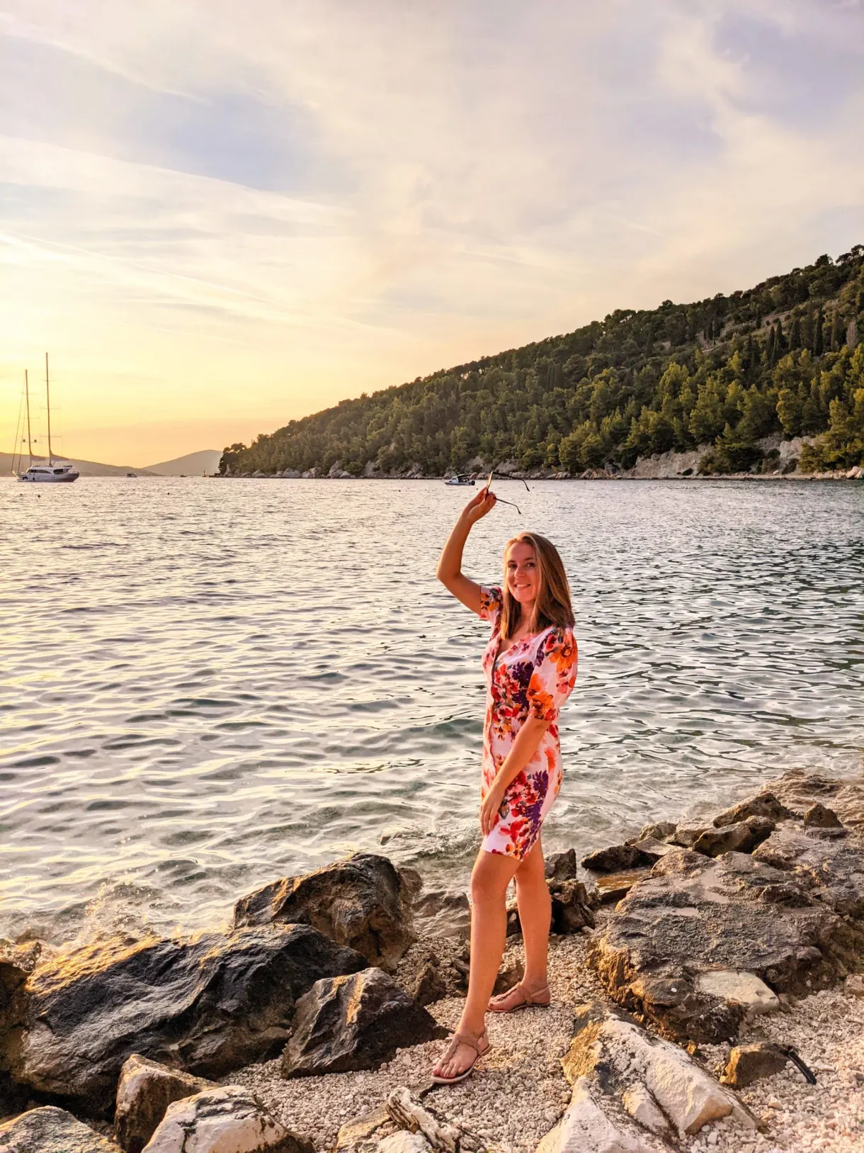 Femme en robe fleurie debout sur les rochers du rivage