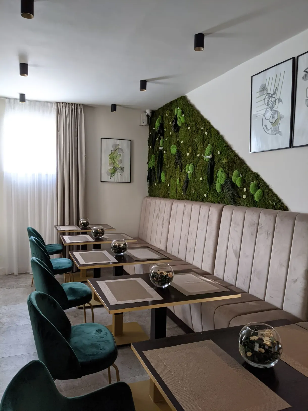 Salle de petit déjeuner aux fauteuils verts et mur végétal