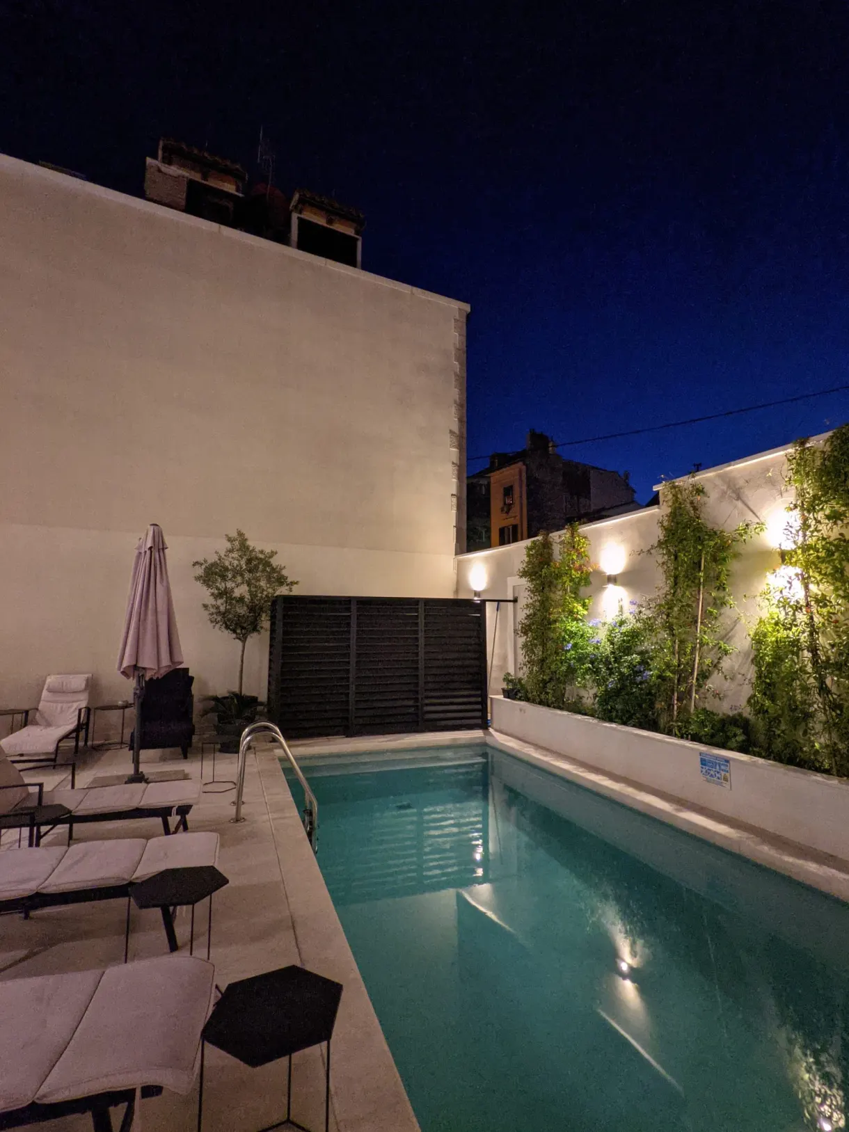Piscine éclairée dans une cour close à la nuit tombée