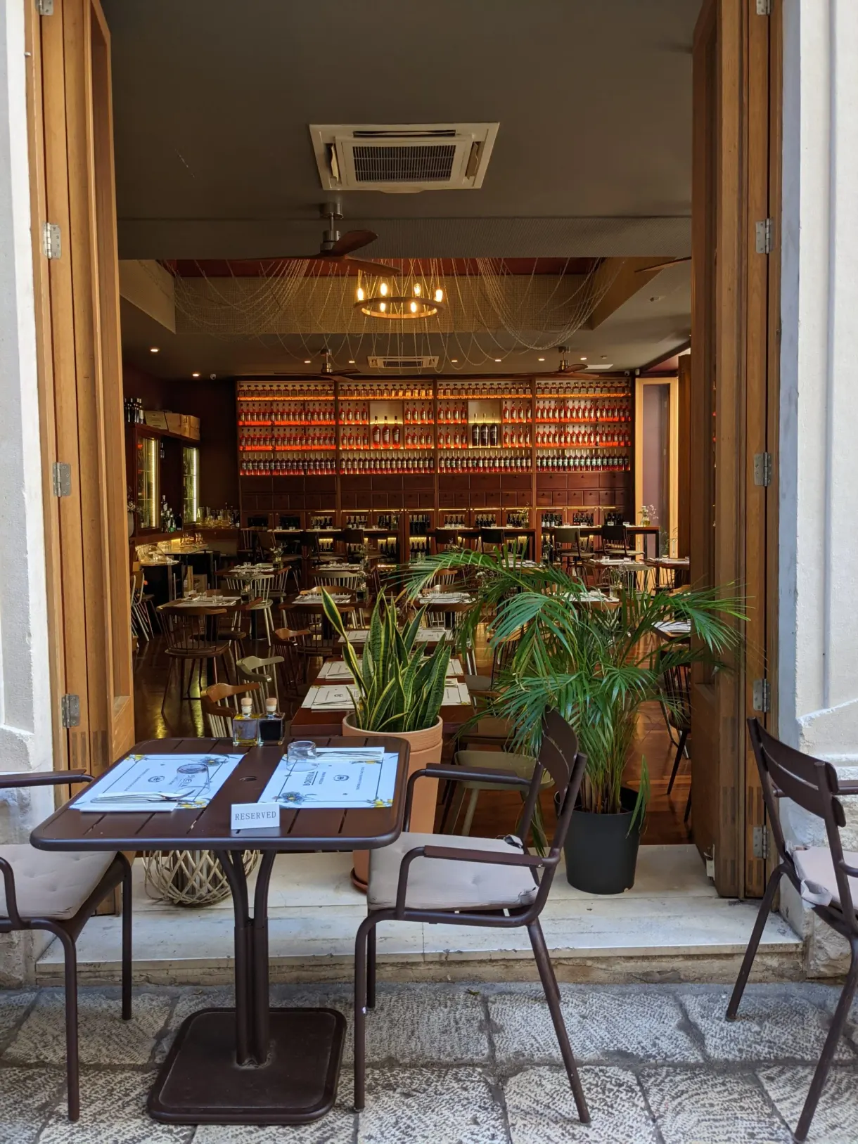 Façade ouverte d'un bar avec tables et plantes vertes