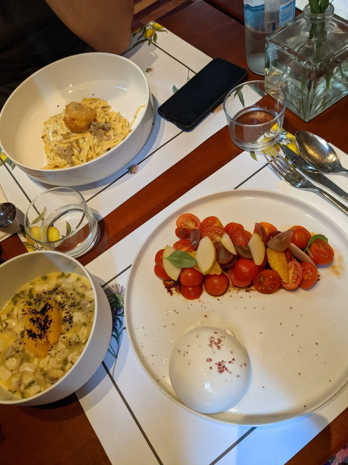 Assiettes de pâtes et salade de tomates sur une table dressée