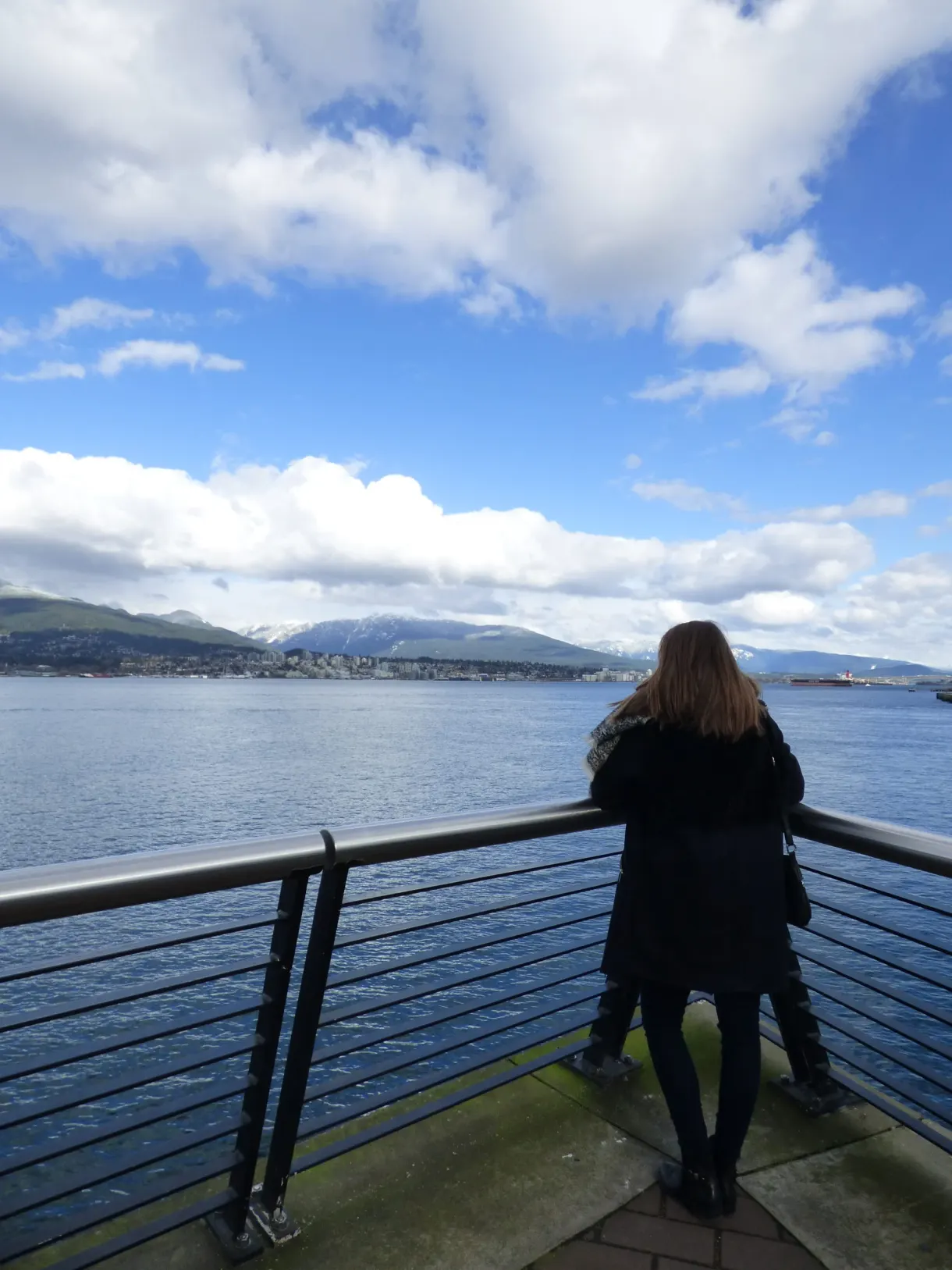 Femme accoudée à une rambarde face à la baie