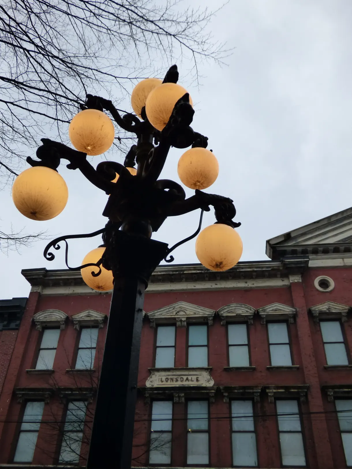 Lampadaire à globes ambrés devant une façade de brique