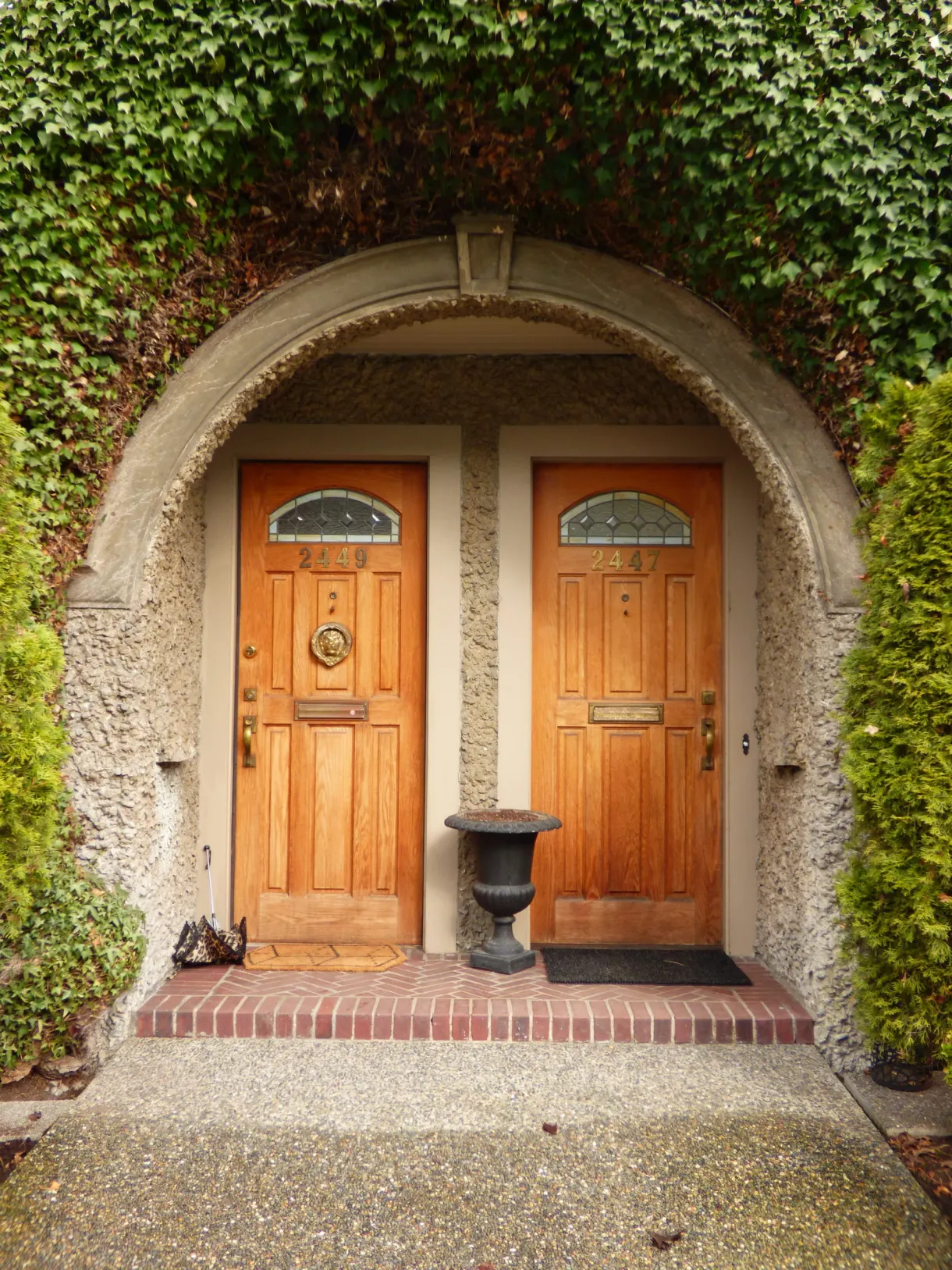 Double porte en bois sous une arche de lierre