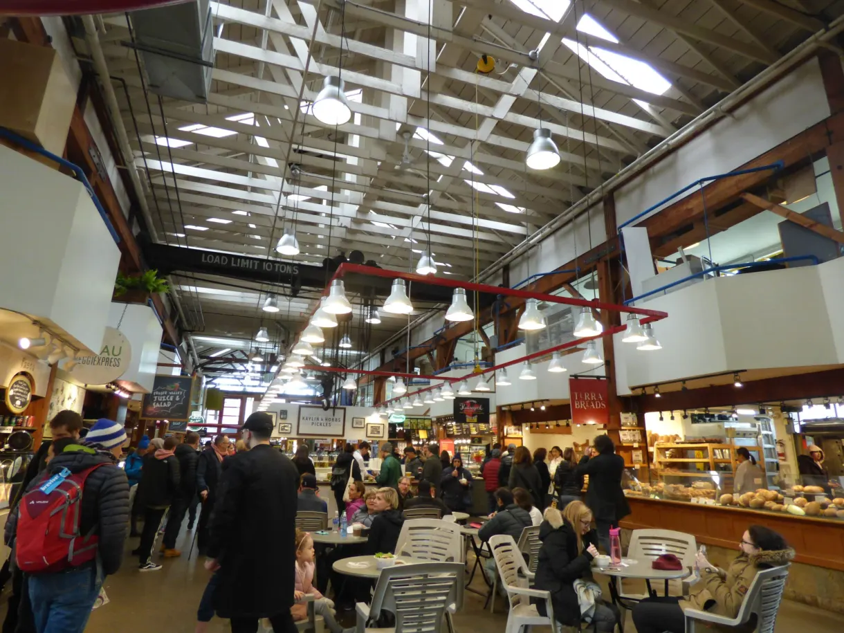 Foule et étals sous la charpente du marché public