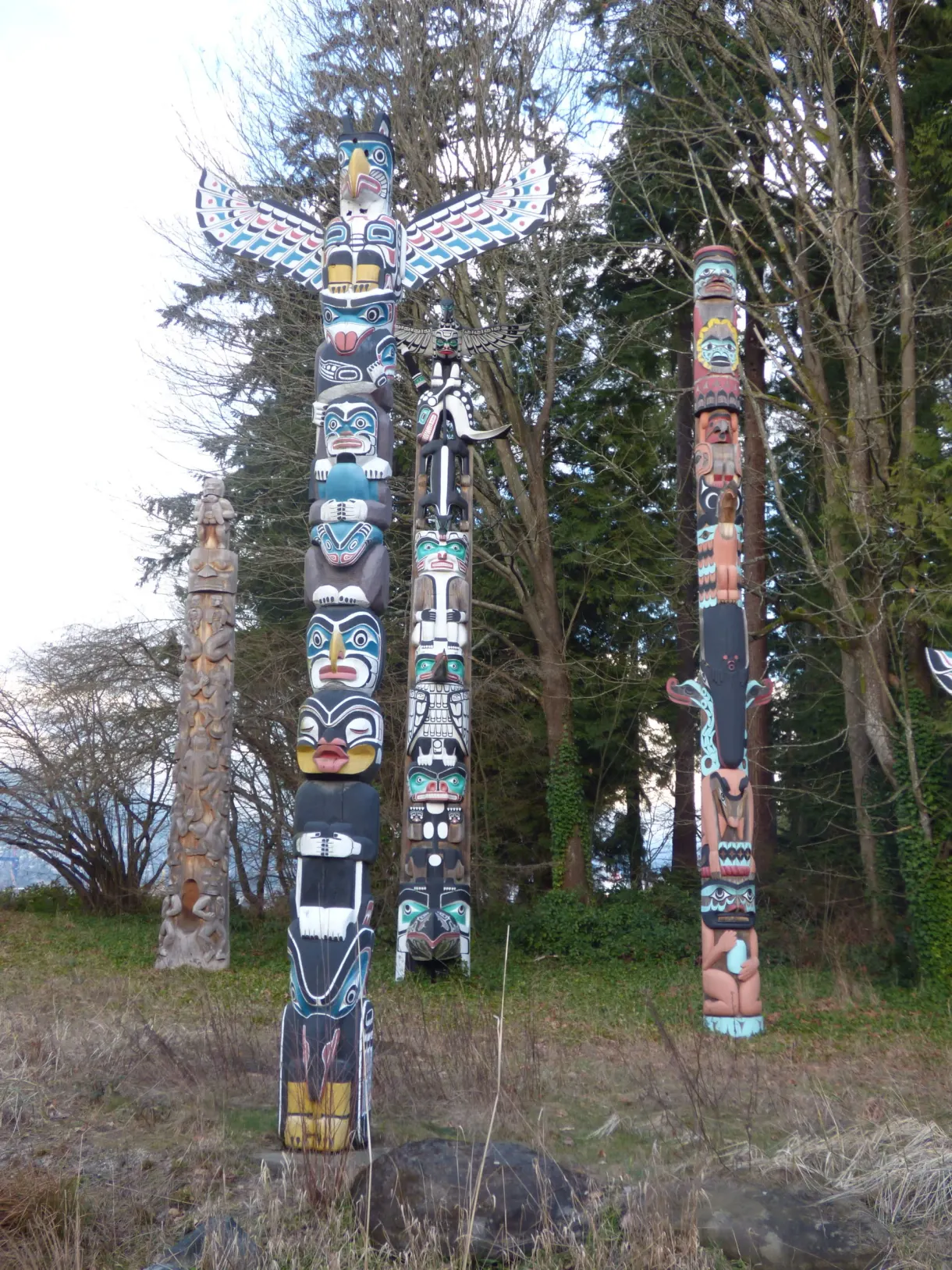 Alignement de totems peints devant les sapins