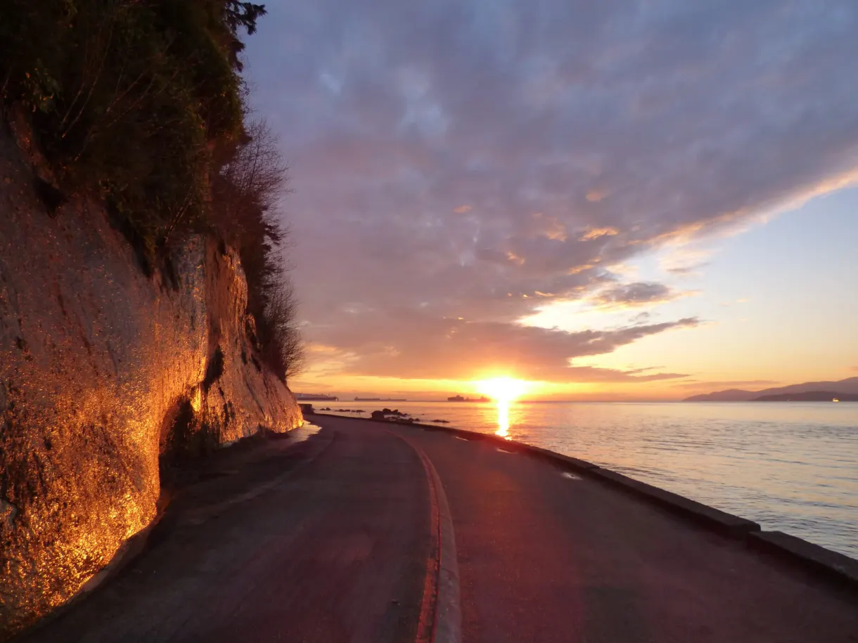 Falaise rousse et route incurvée sous un ciel orangé