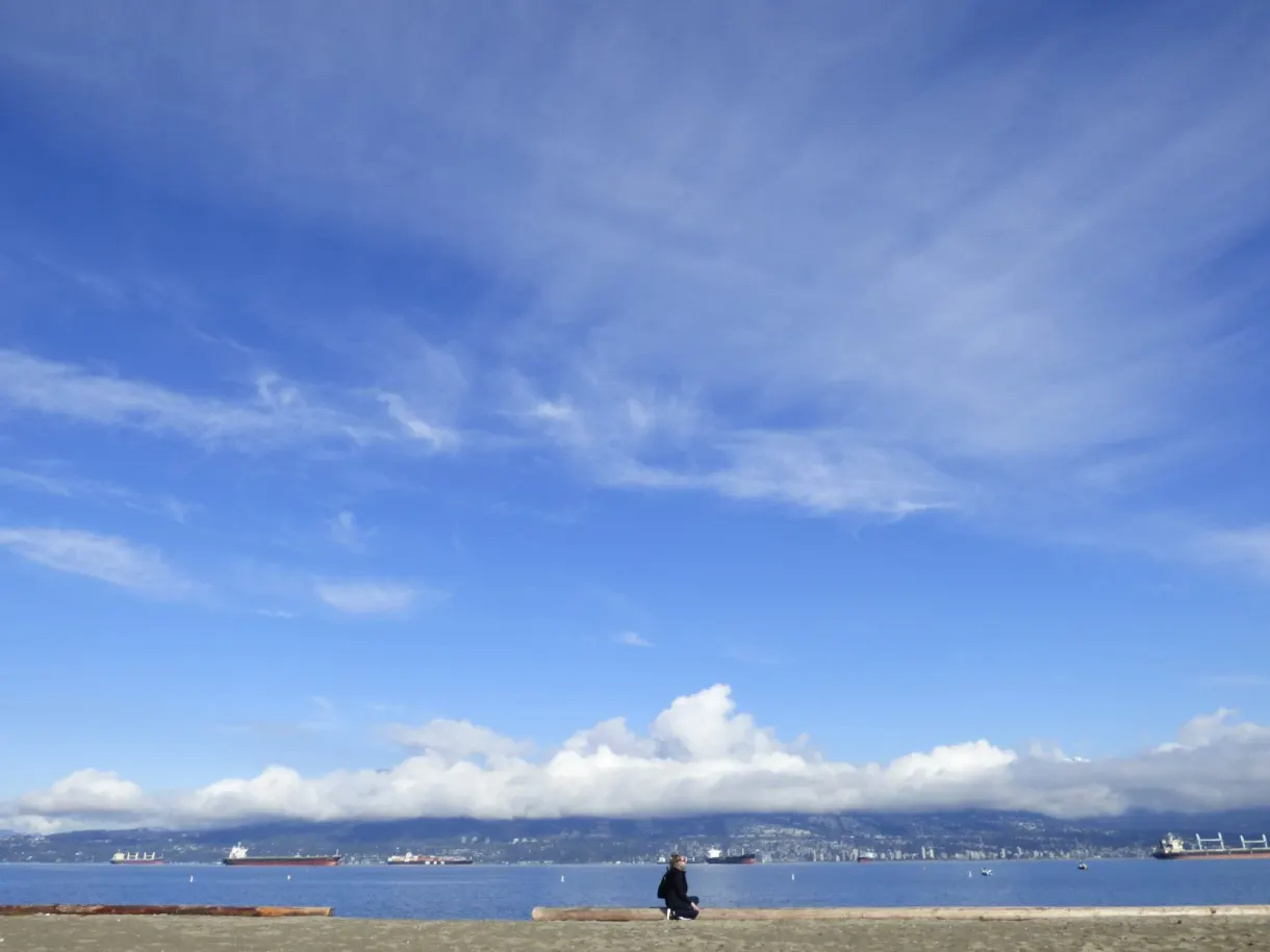 Silhouette assise seule sous un vaste ciel de plage