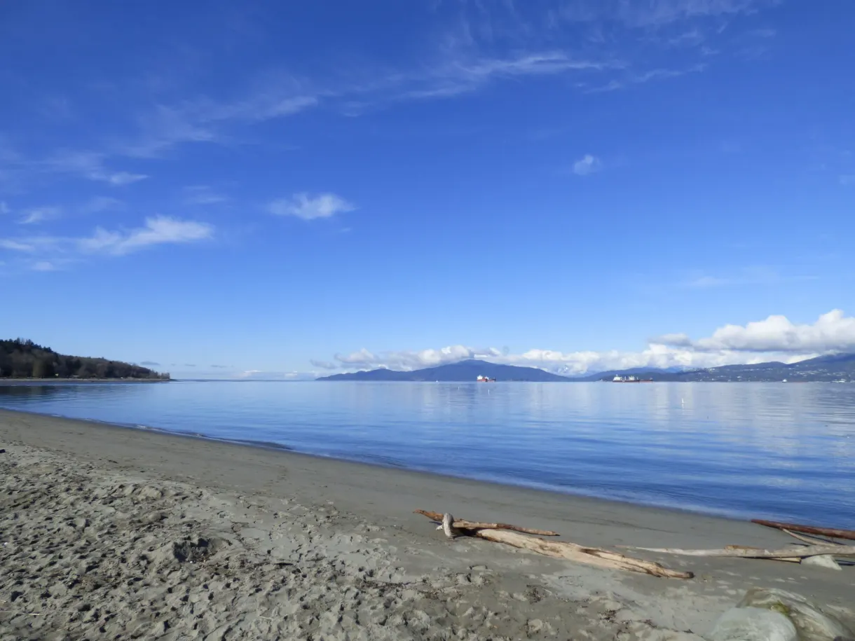 Sable brun et mer bleue jusqu'aux montagnes