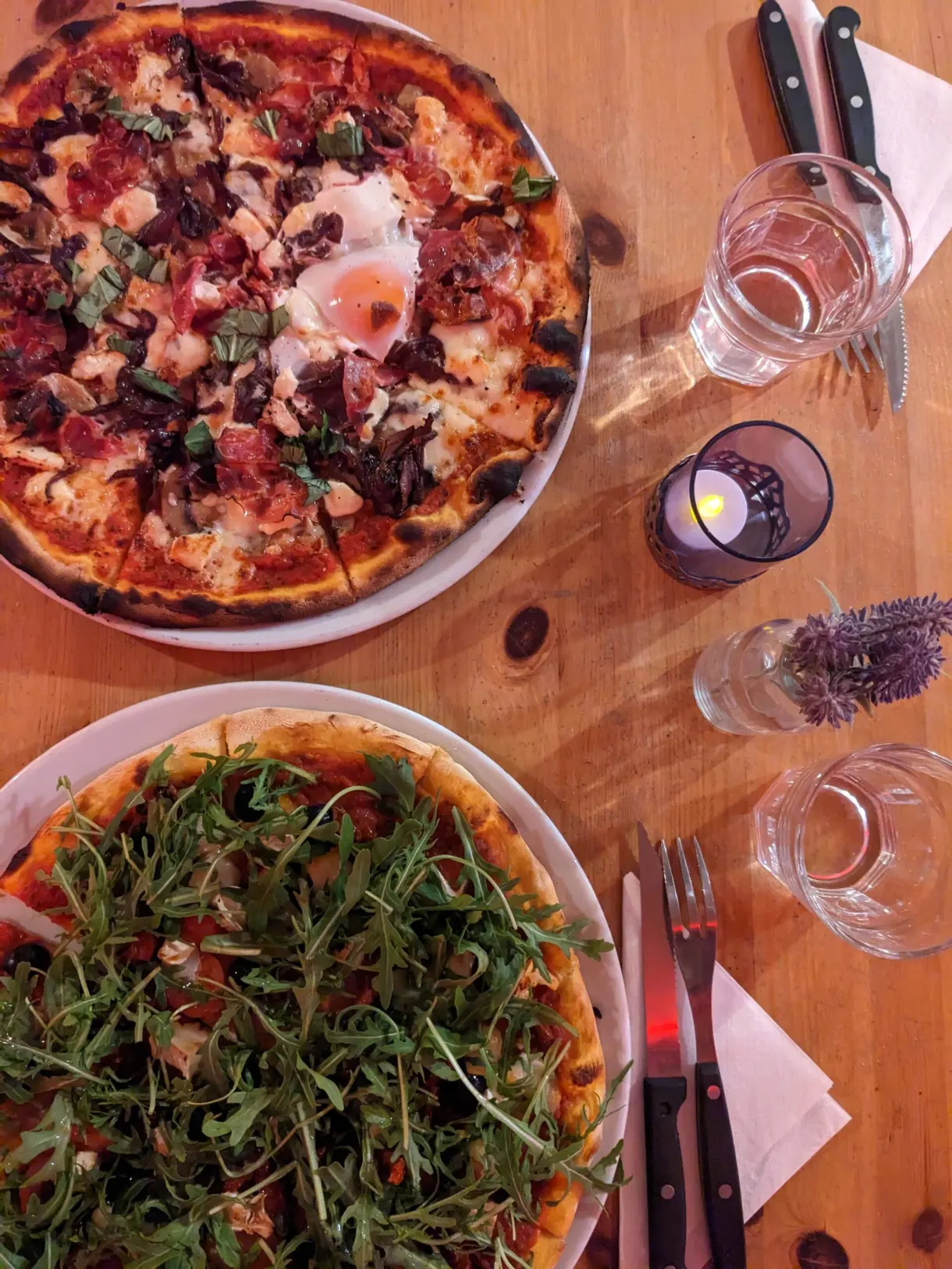 Deux pizzas garnies servies sur une table en bois