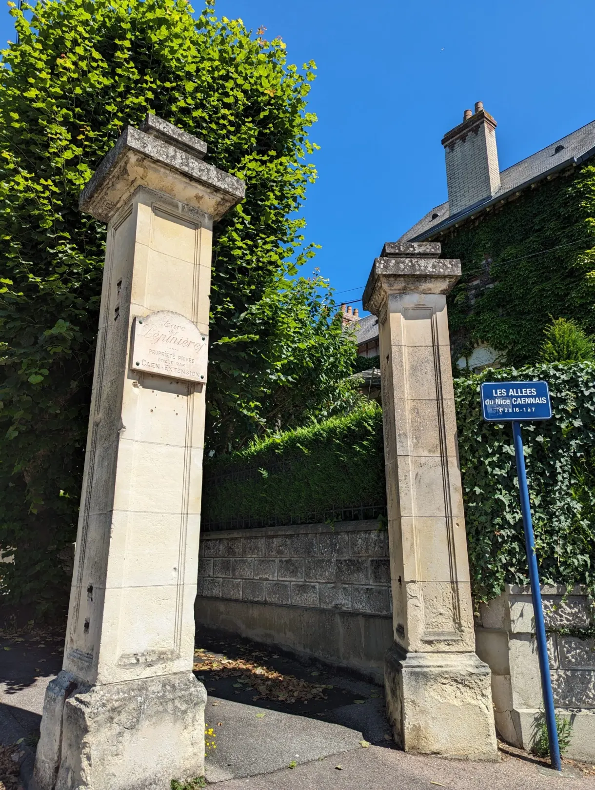 Deux hauts piliers de pierre marquant l'entrée d'une allée ombragée